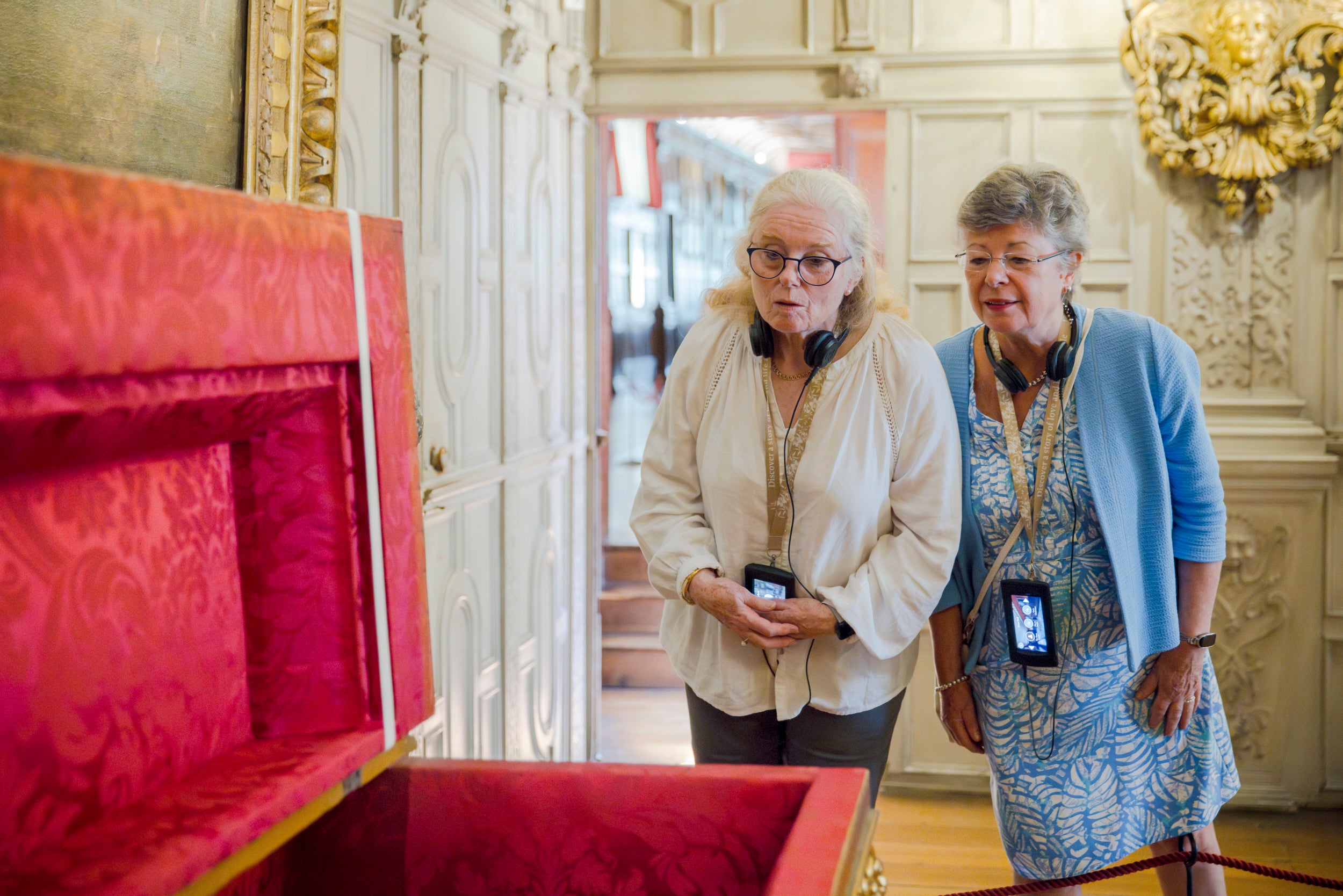 Two people looking into a large trunk that has the top lifted to show a bright red lining.