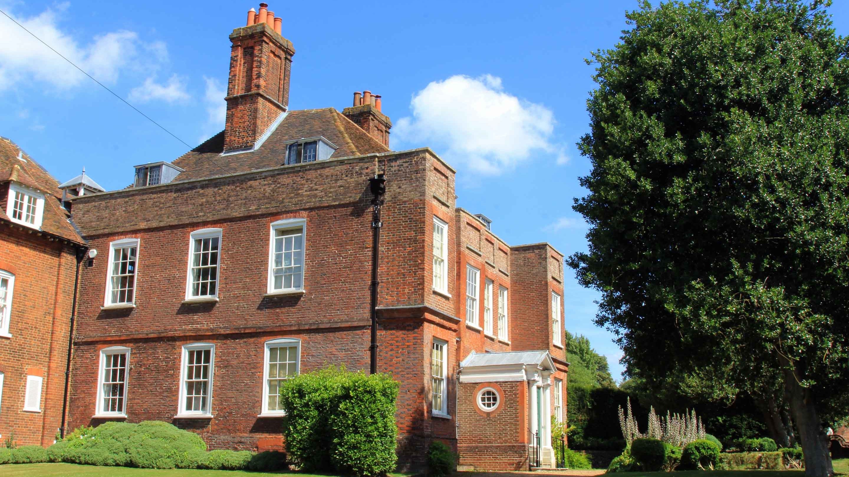 The red brick house at Owletts with large sash windows against a blue sky