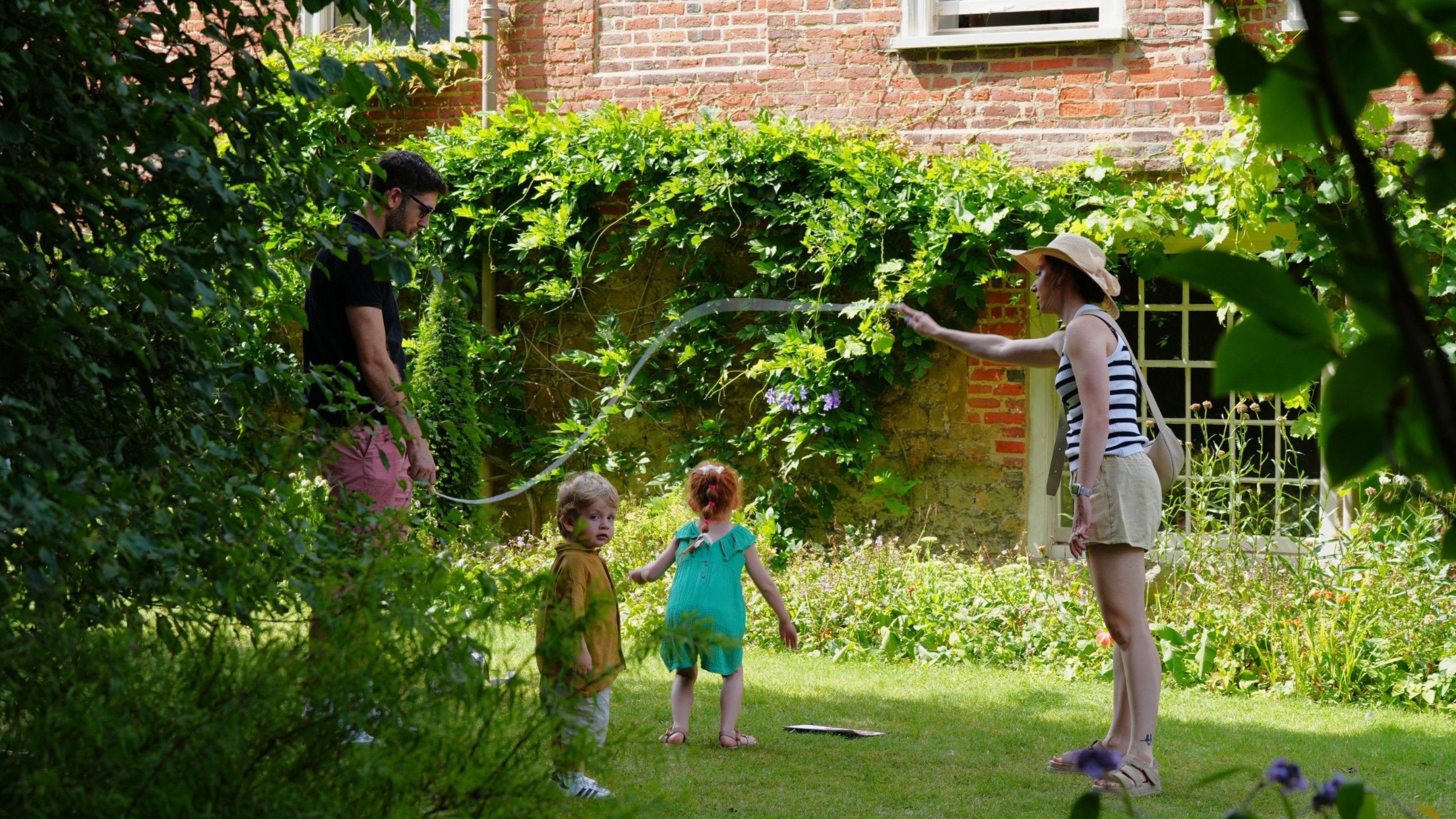Family playing jump rope in the garden at Quebec House, Kent