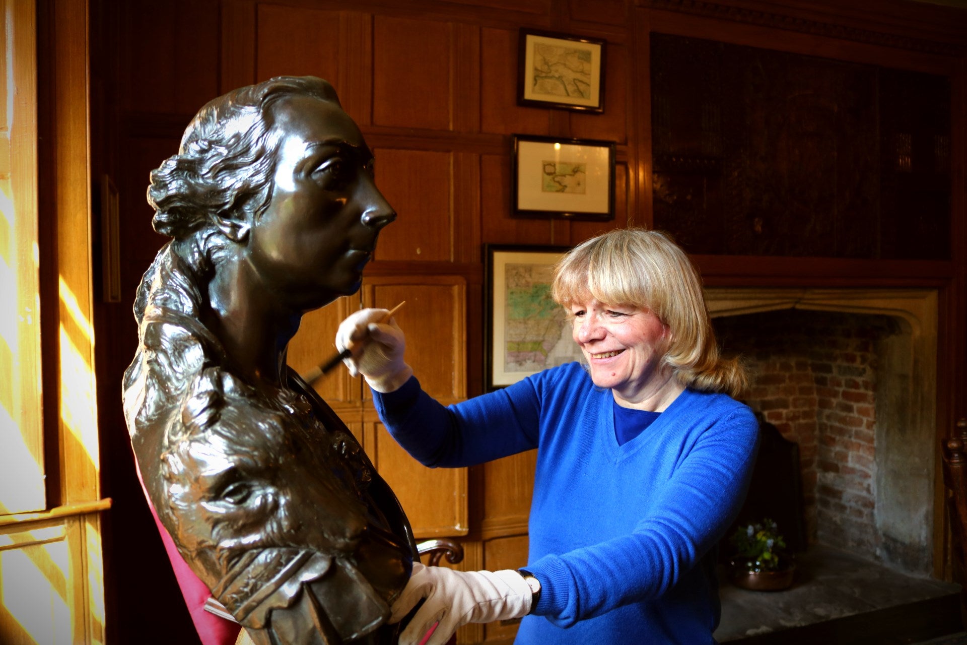 Conservation volunteer cleaning a bust of James Wolfe at Quebec House, Kent