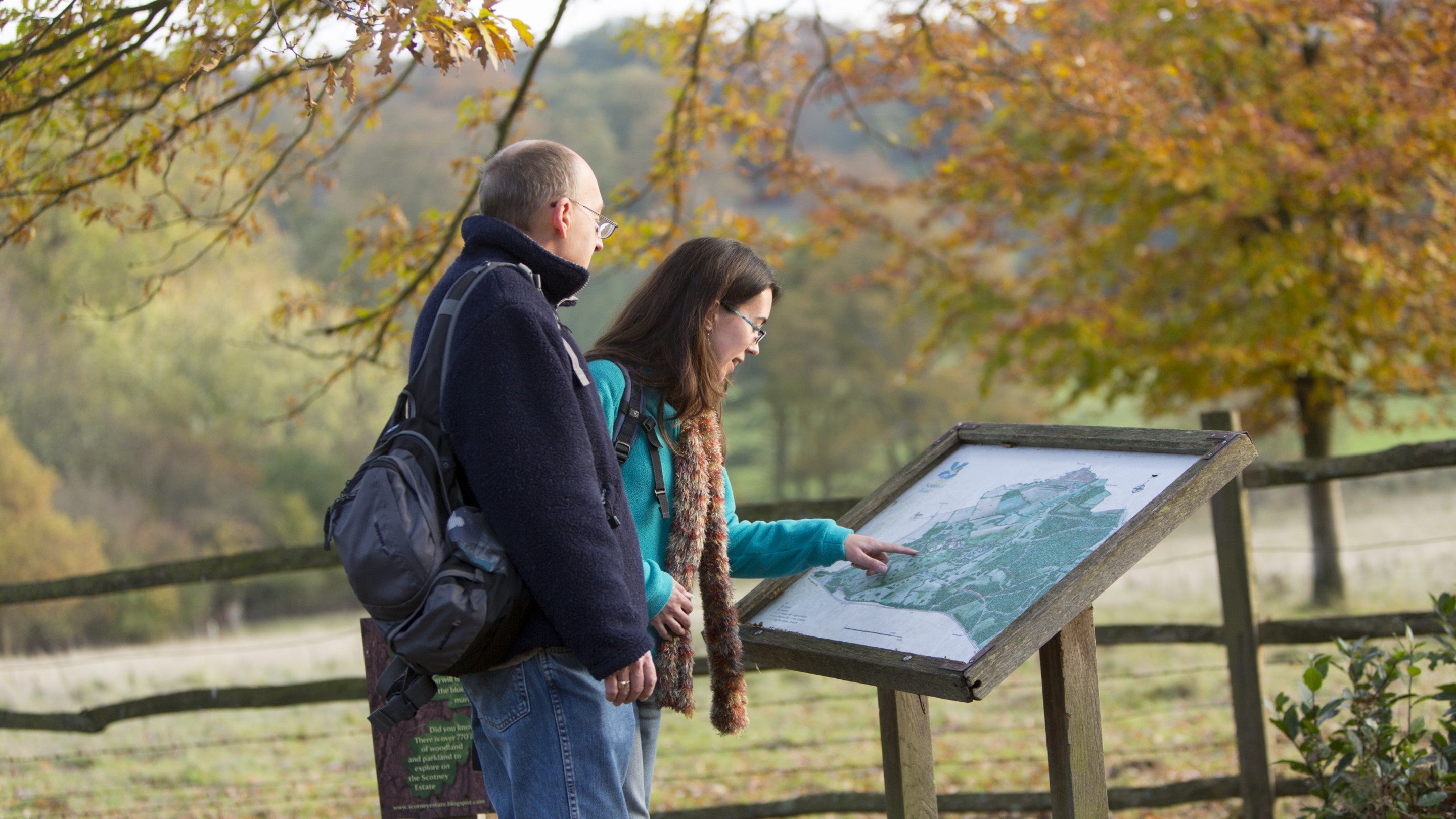 Two visitors looking at a map in the autumn at Scotney Castle, Kent