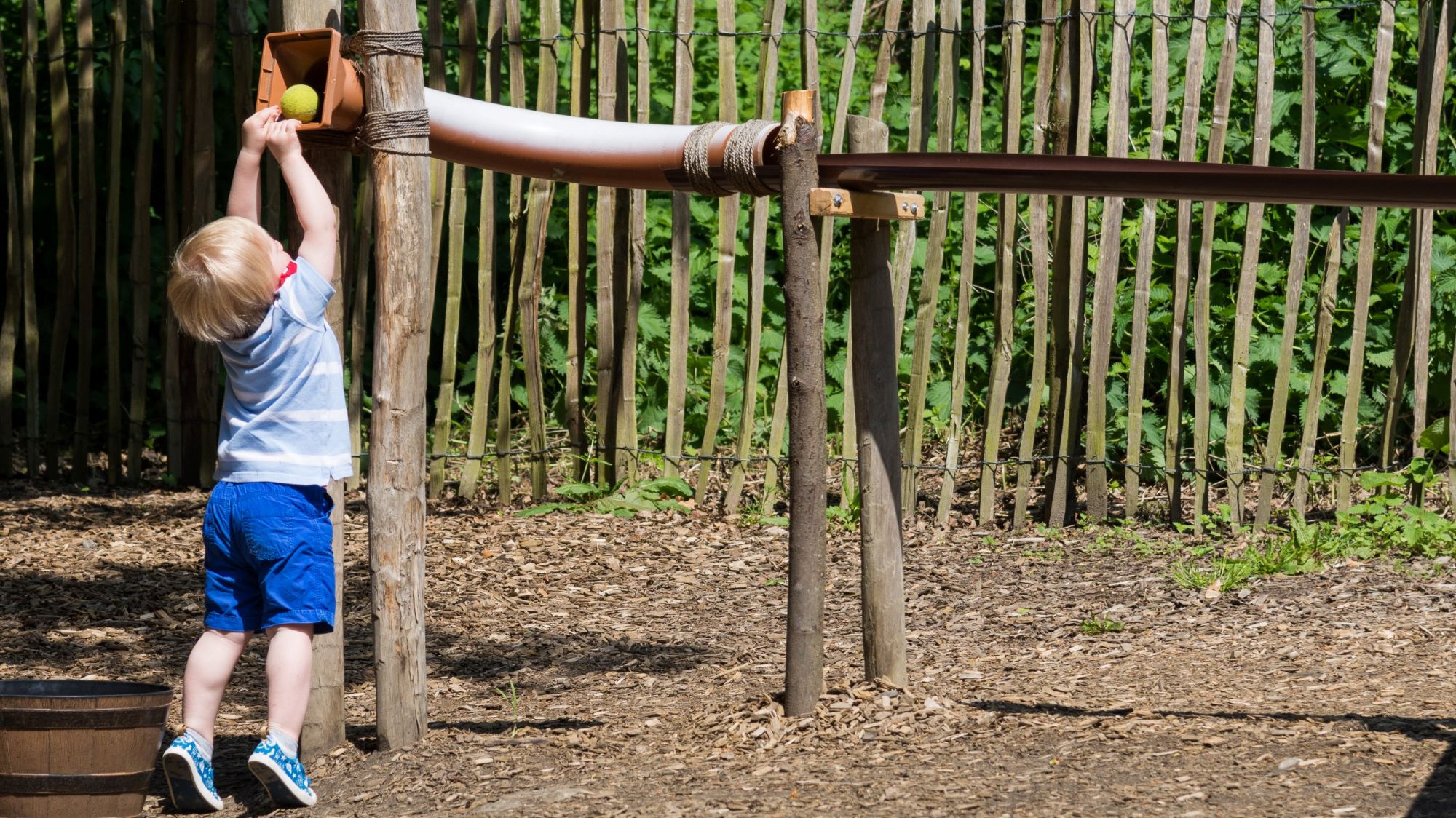 A small child playing with the ball chute in the Badger & Pepper play area at Scotney Castle