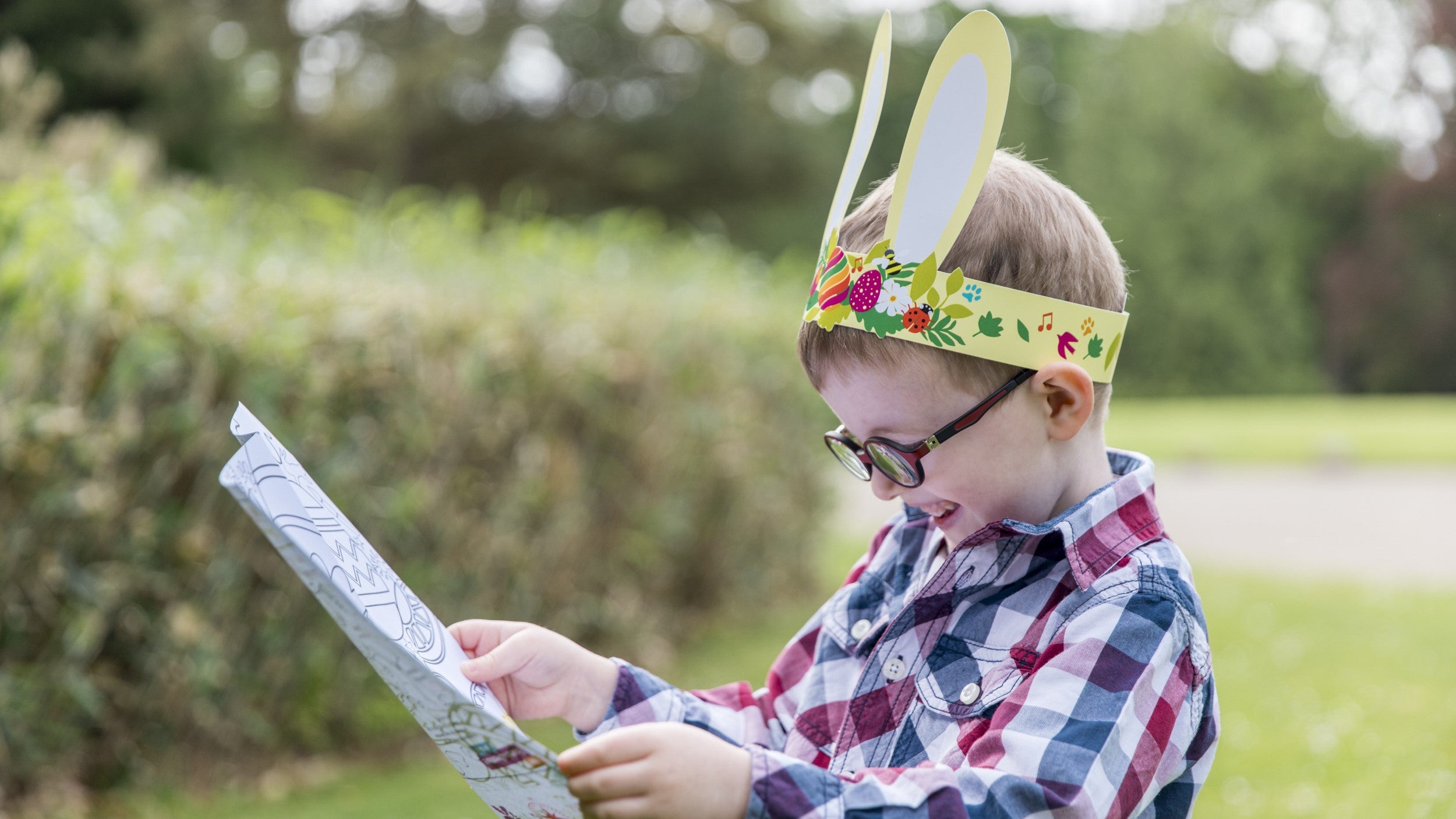 Small child with glasses and paper bunny ears looking at a map
