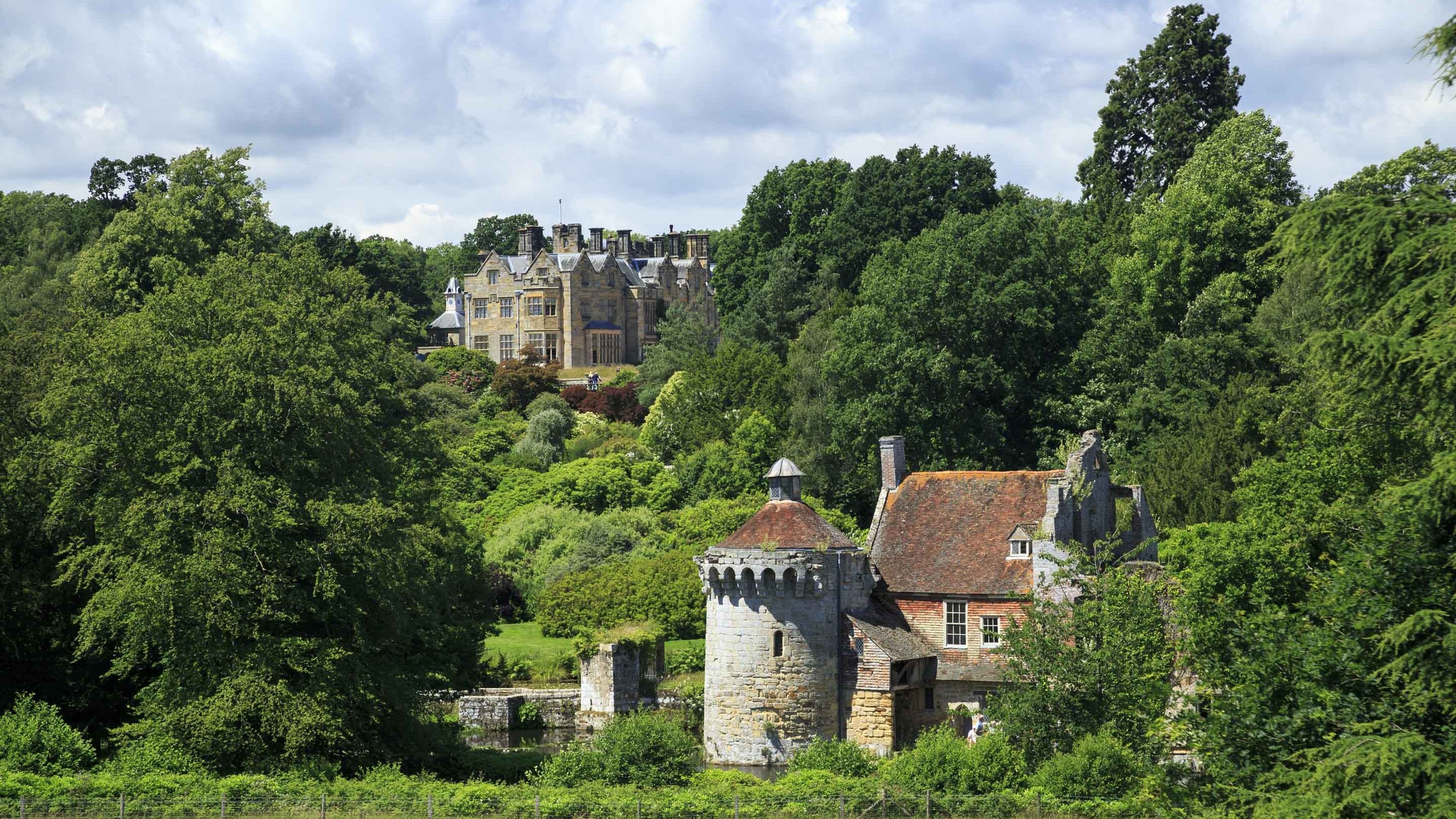 A scenic images of the house and ruins of the fourteenth-century moated castle at Scotney Castle, Kent surrounded by garden and trees