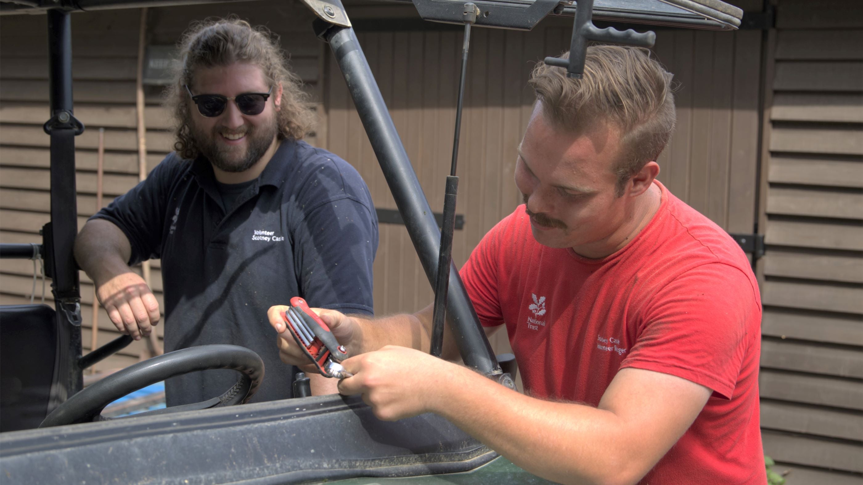 Two adults working on a vehicle