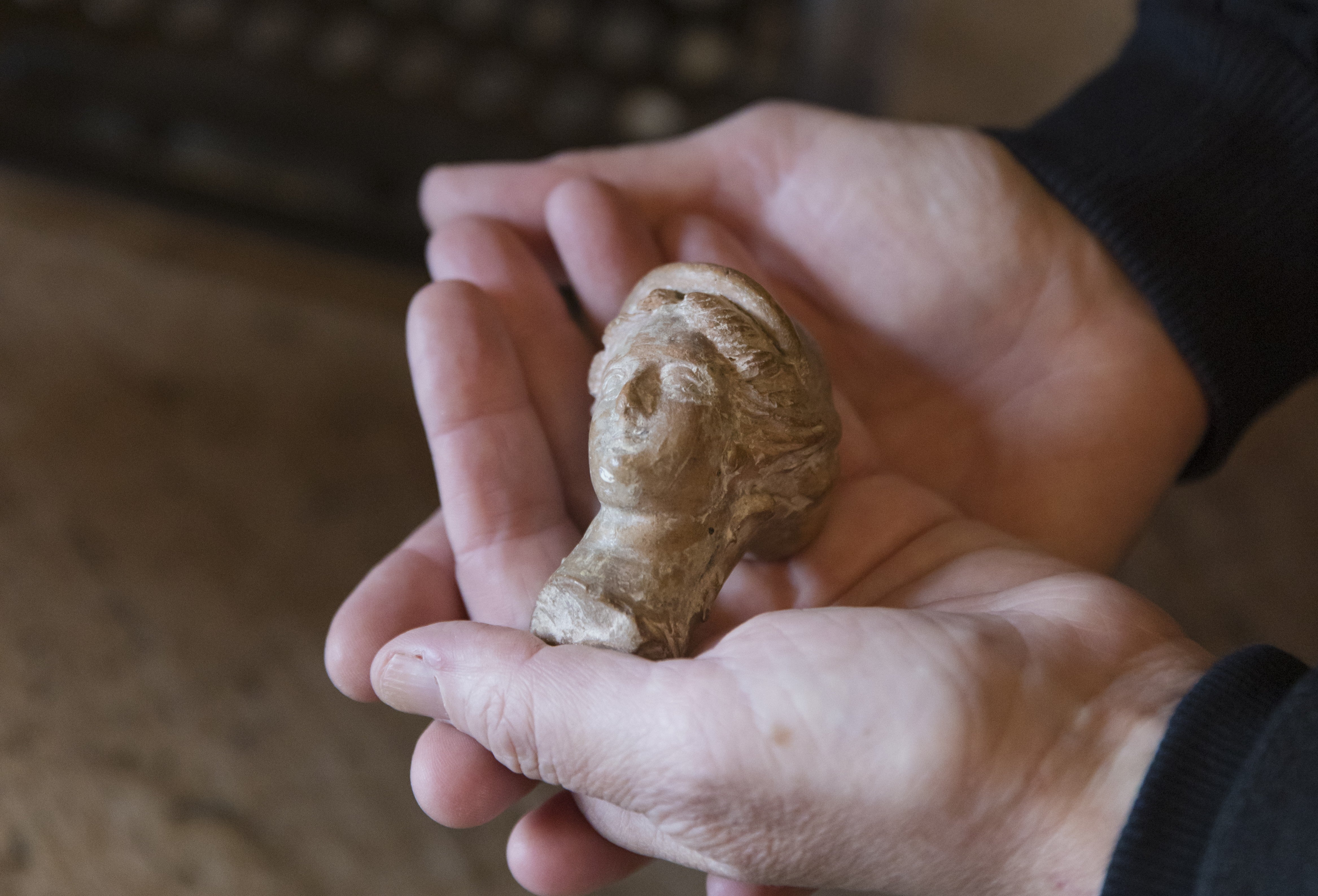 The head of an ancient Greek statue of Demeter is held in a pair of hands
