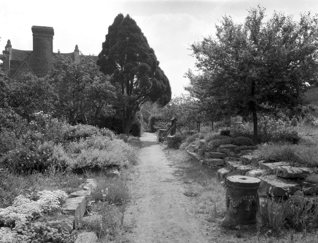 A black and white image of a garden path and stacked stone slabs on the right hand side