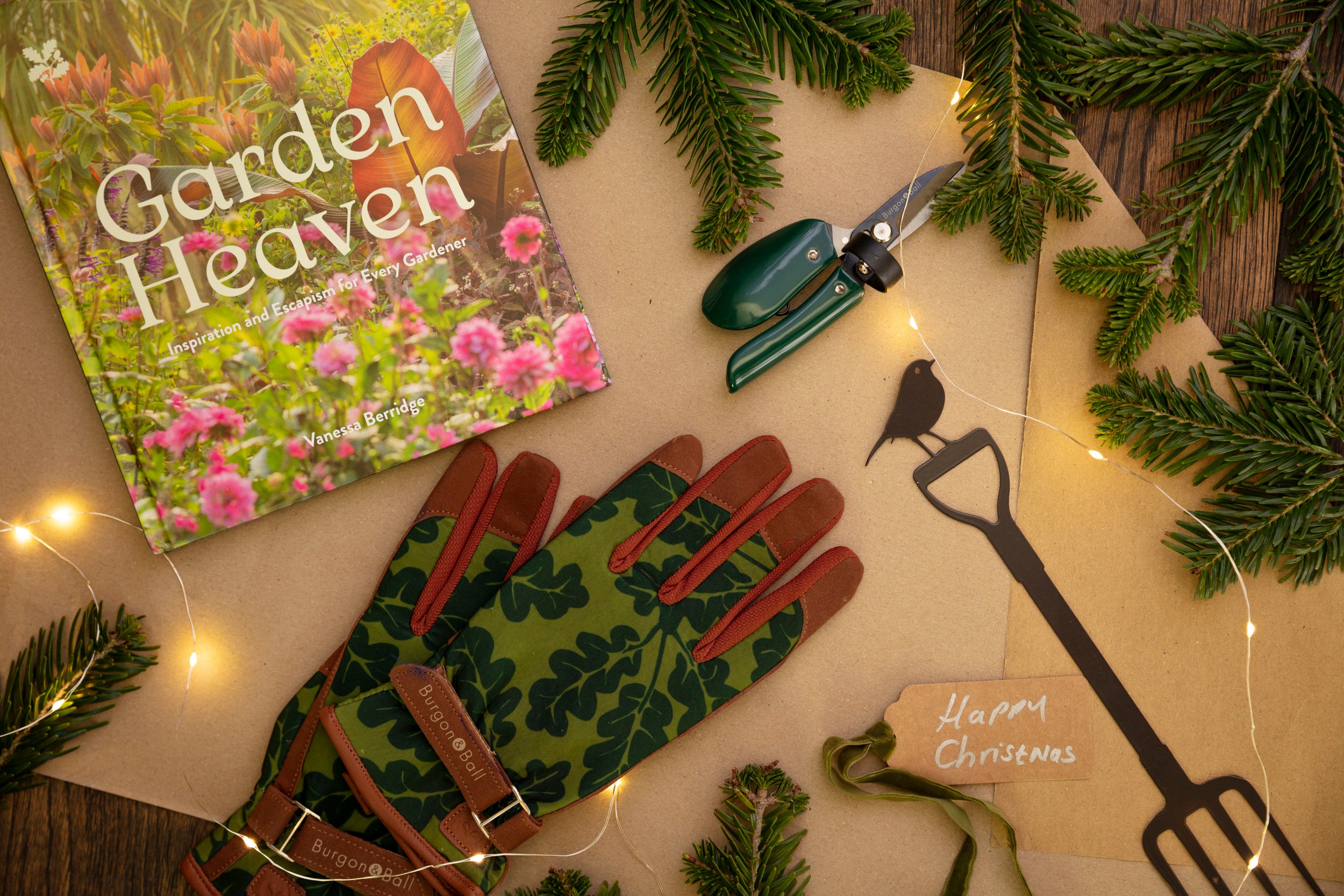 Fairy lights intertwined with gardening gloves, a book and gardening fork