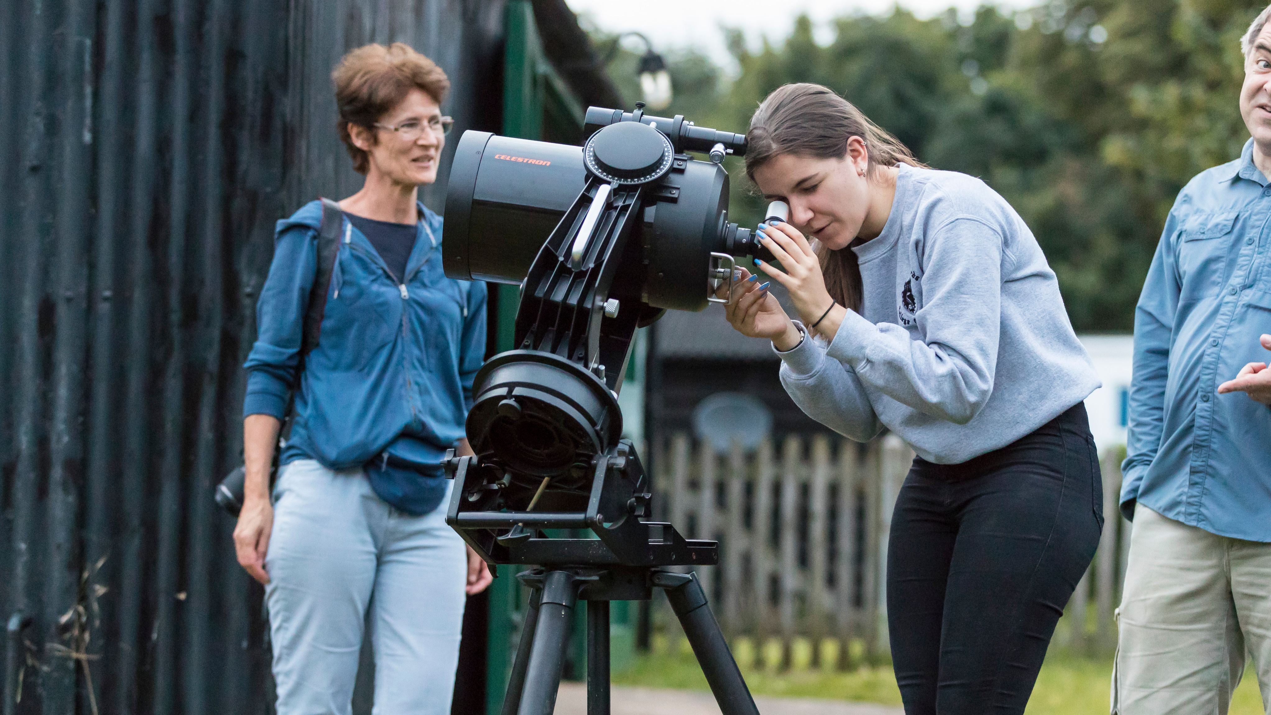 Image of a young lady using an astronomical telescope