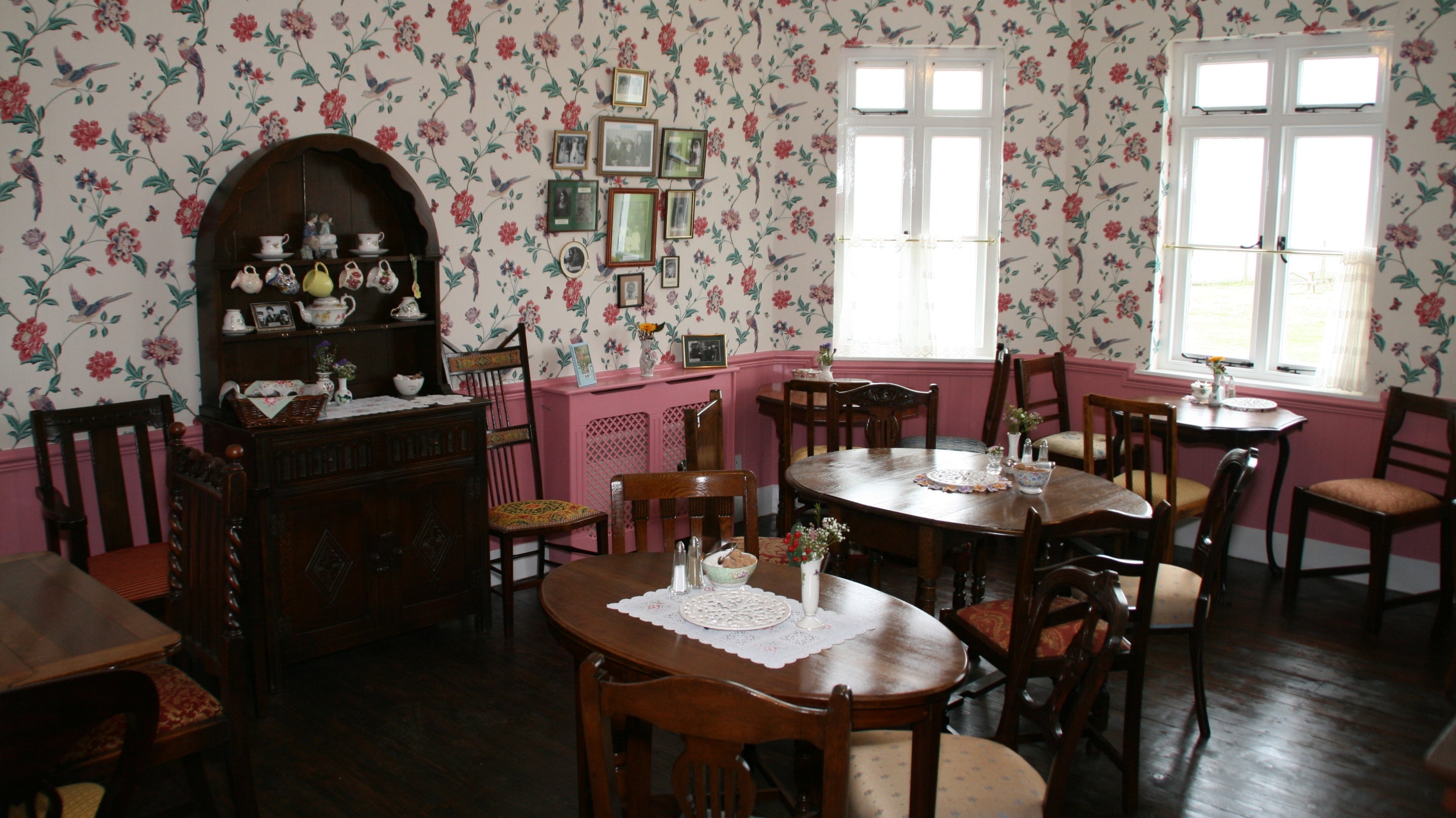 Image of the interior of Mrs Knotts Tea Room with tables and chairs and flowered wallpaper in a 1950's style