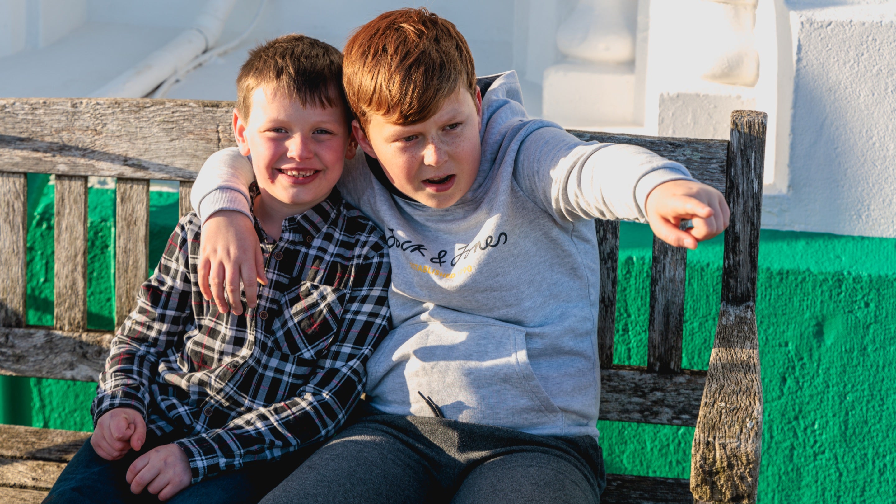Two children laughing, sitting on a bench outside South Foreland Lighthouse