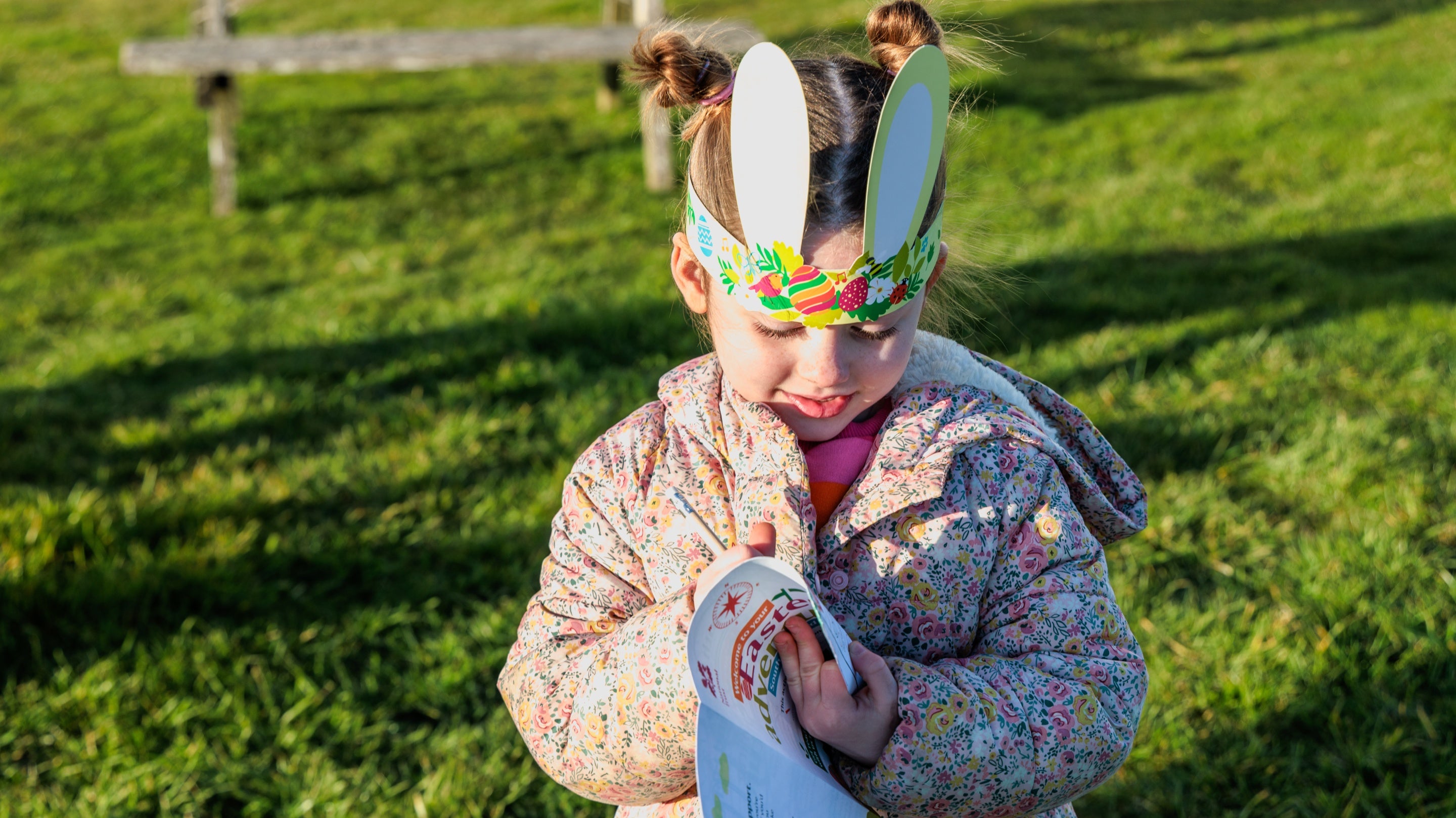 Image of a child wearing bunny ears looking intently at her Easter trail sheet