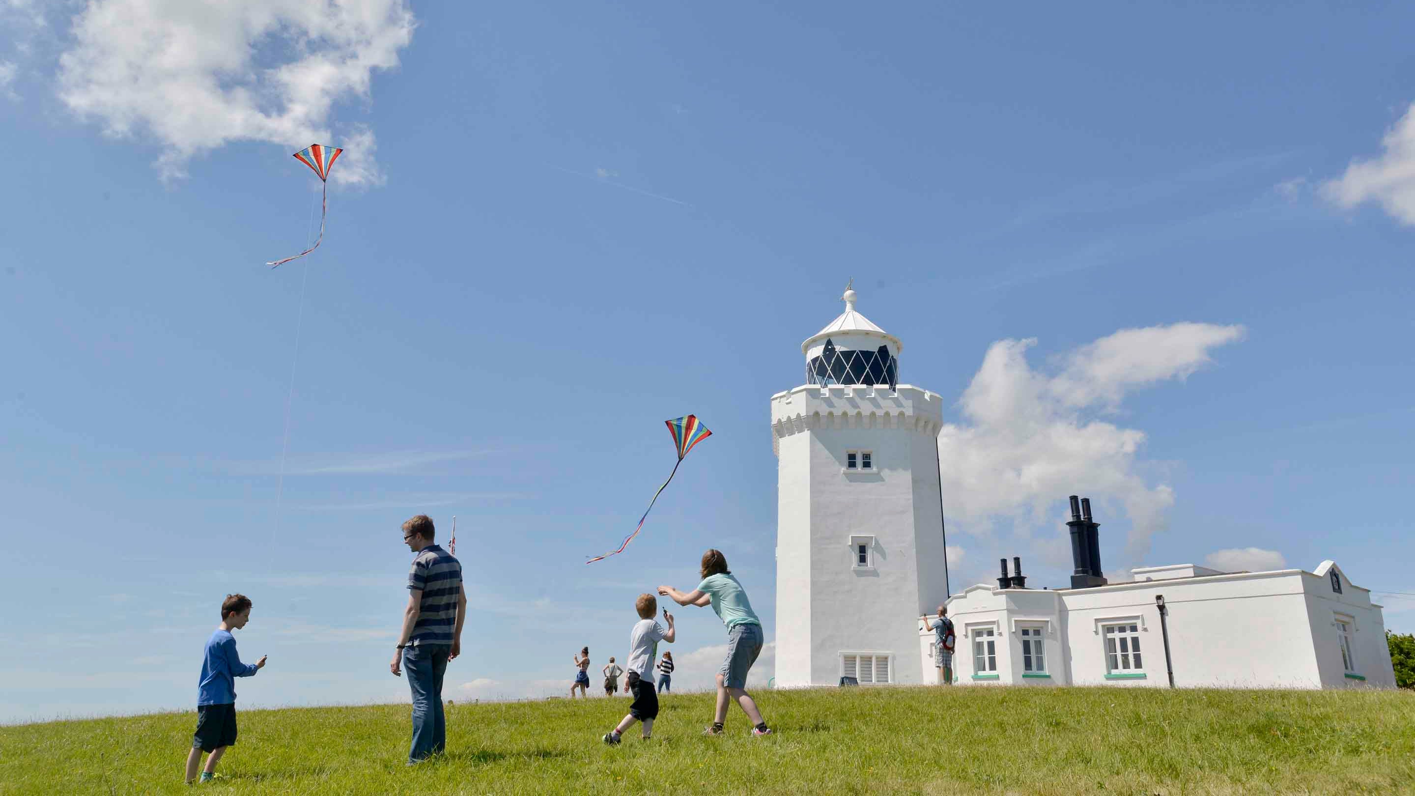 Family visitors flying kites by the South Foreland Lighthouse, Kent, on a sunny day in August