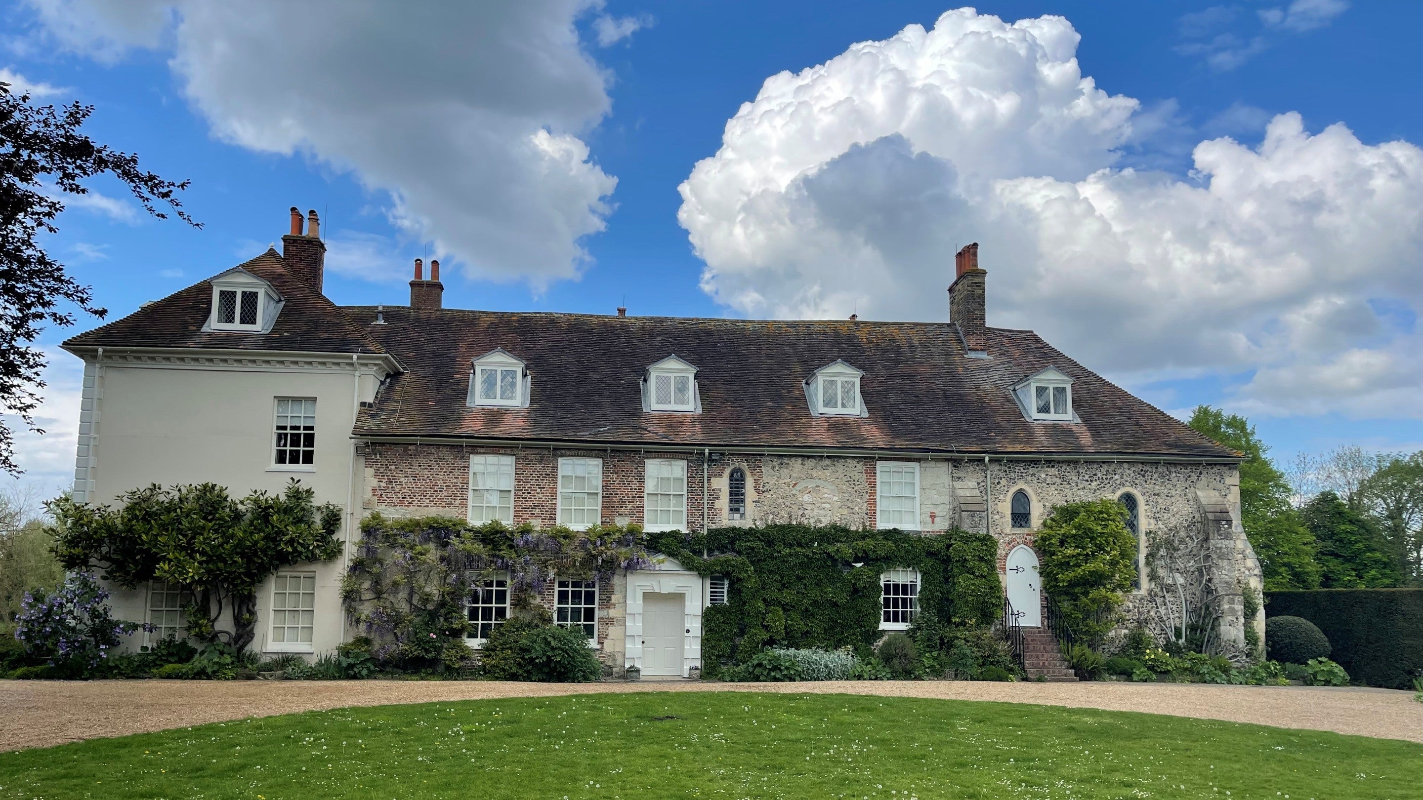 View of the front of the house and chapel at St John's Jerusalem on a sunny day with white clouds and a blue sky