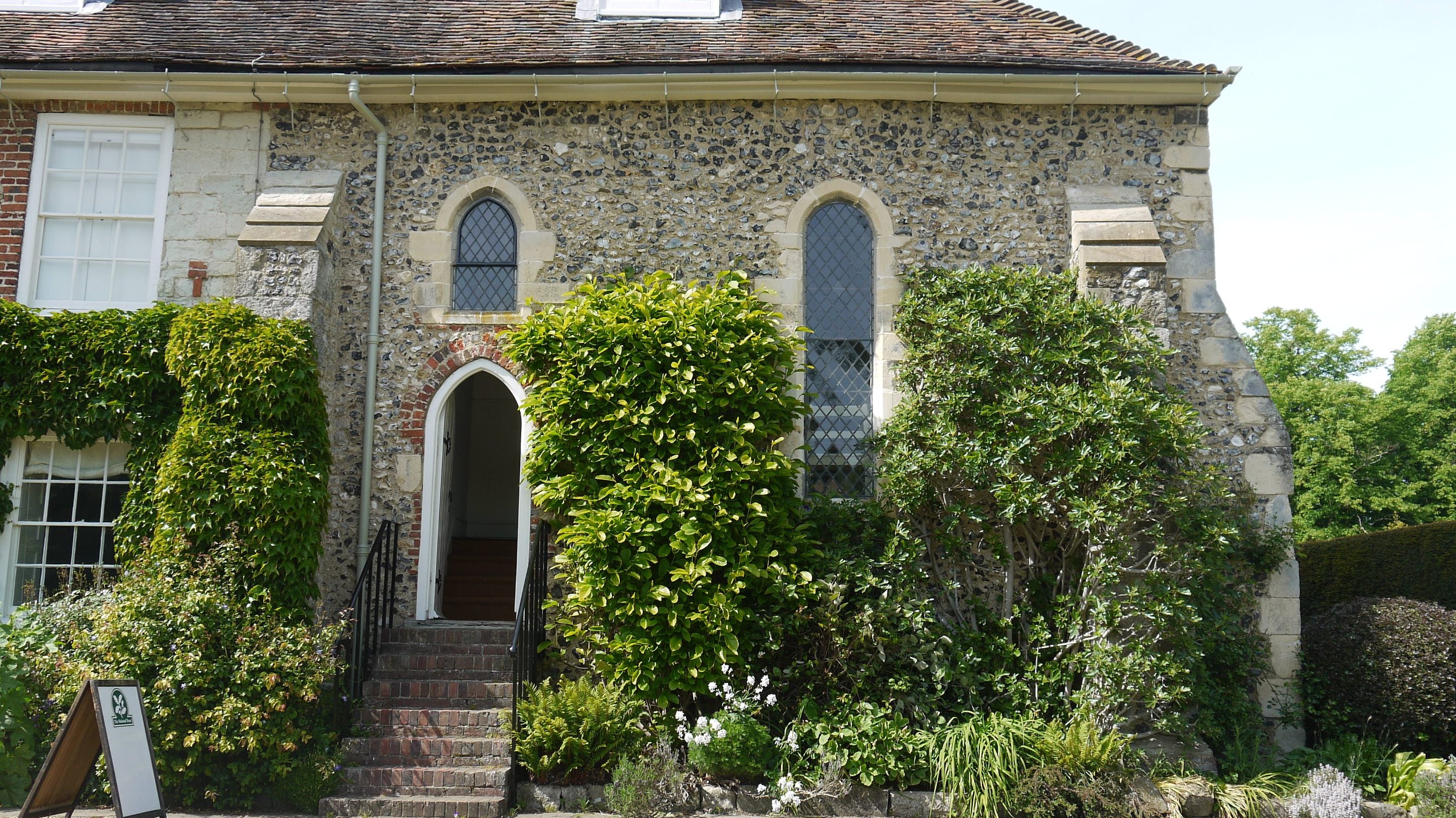 Image of a medieval flint-walled chapel with steps leading up to the entrance