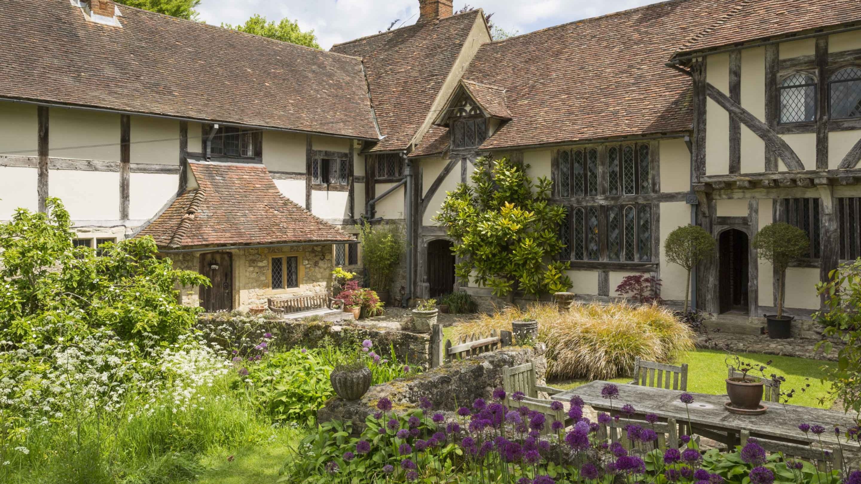 View of the Courtyard Garden at Stoneacre in summer with purple alliums in bloom