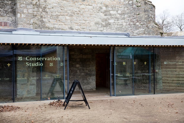 Entrance to a grey brick building, which has large glass doors and Conservation Studio written on one of the doors on the left.