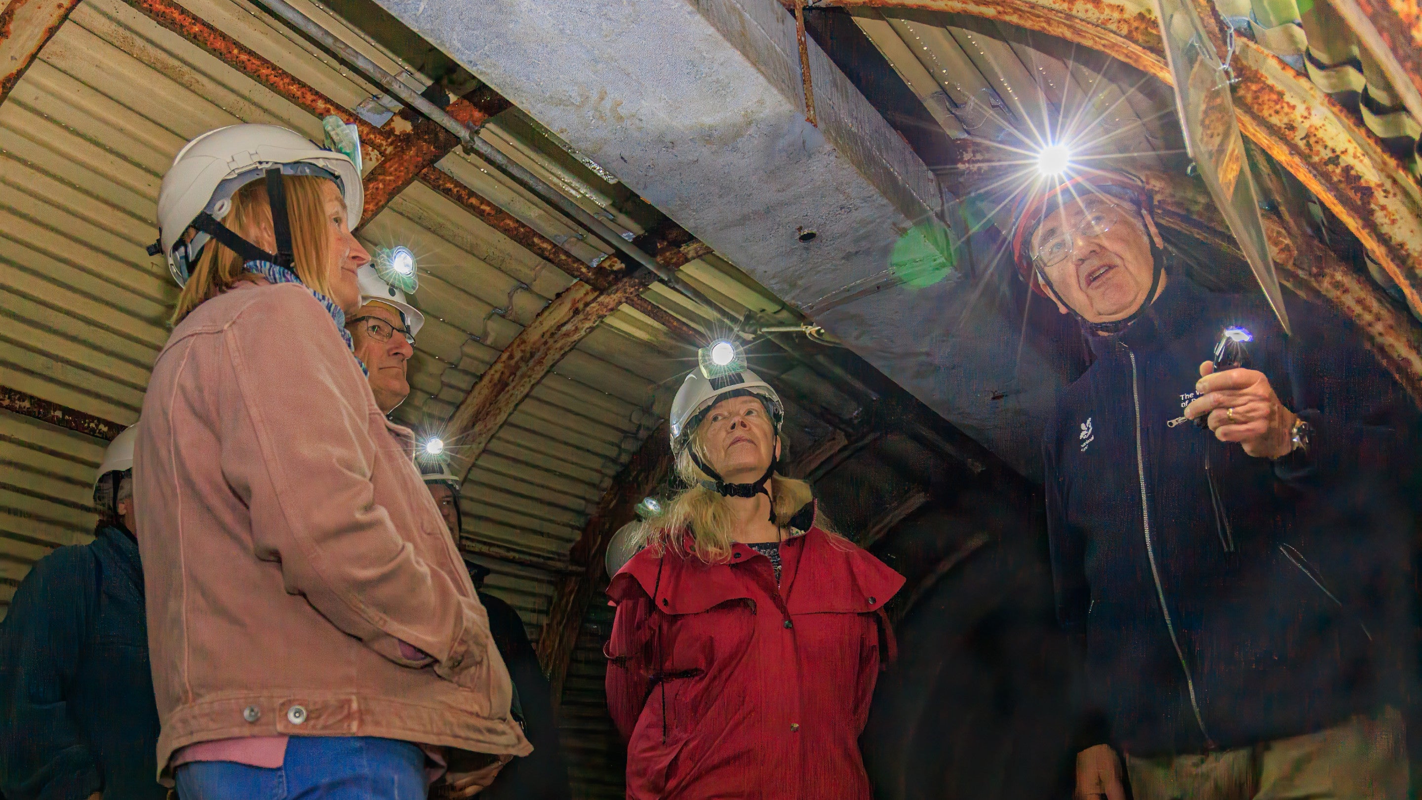 Image of a National Trust guide explaining a picture of the tunnels during wartime to visitors at Fan Bay Deep Shelter