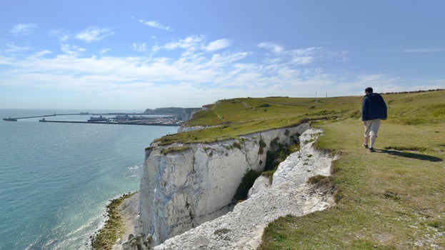 Image of visitor walking along the clifftop at the White Cliffs of Dover, Kent on a sunny day in August