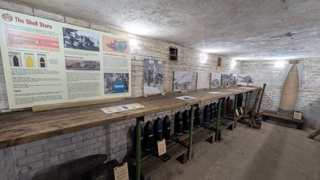 Image of an underground room with interpretation panels and dummy shells and a bench on the left hand side