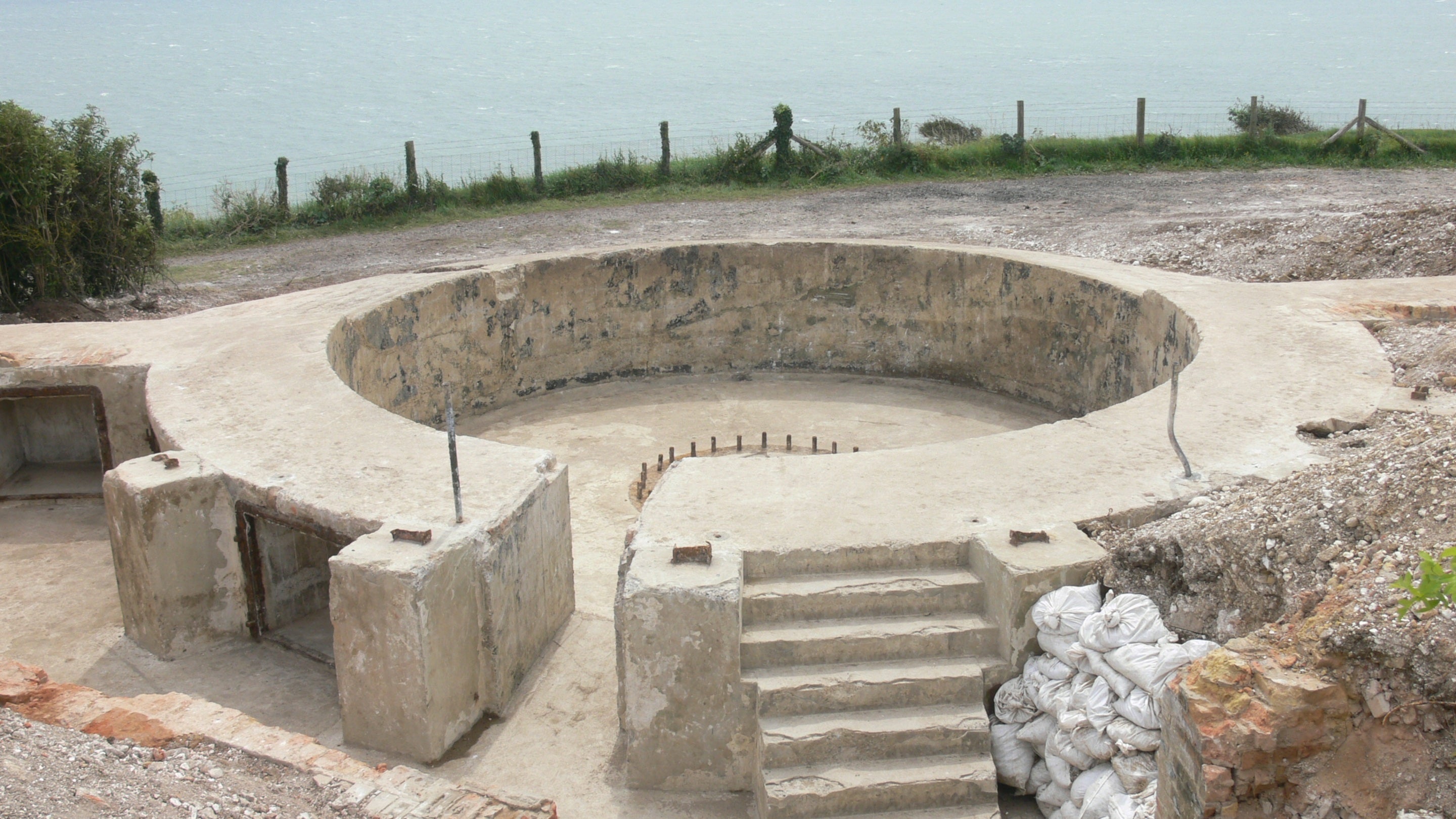 Image of a circular concrete gun emplacement with the sea in the background