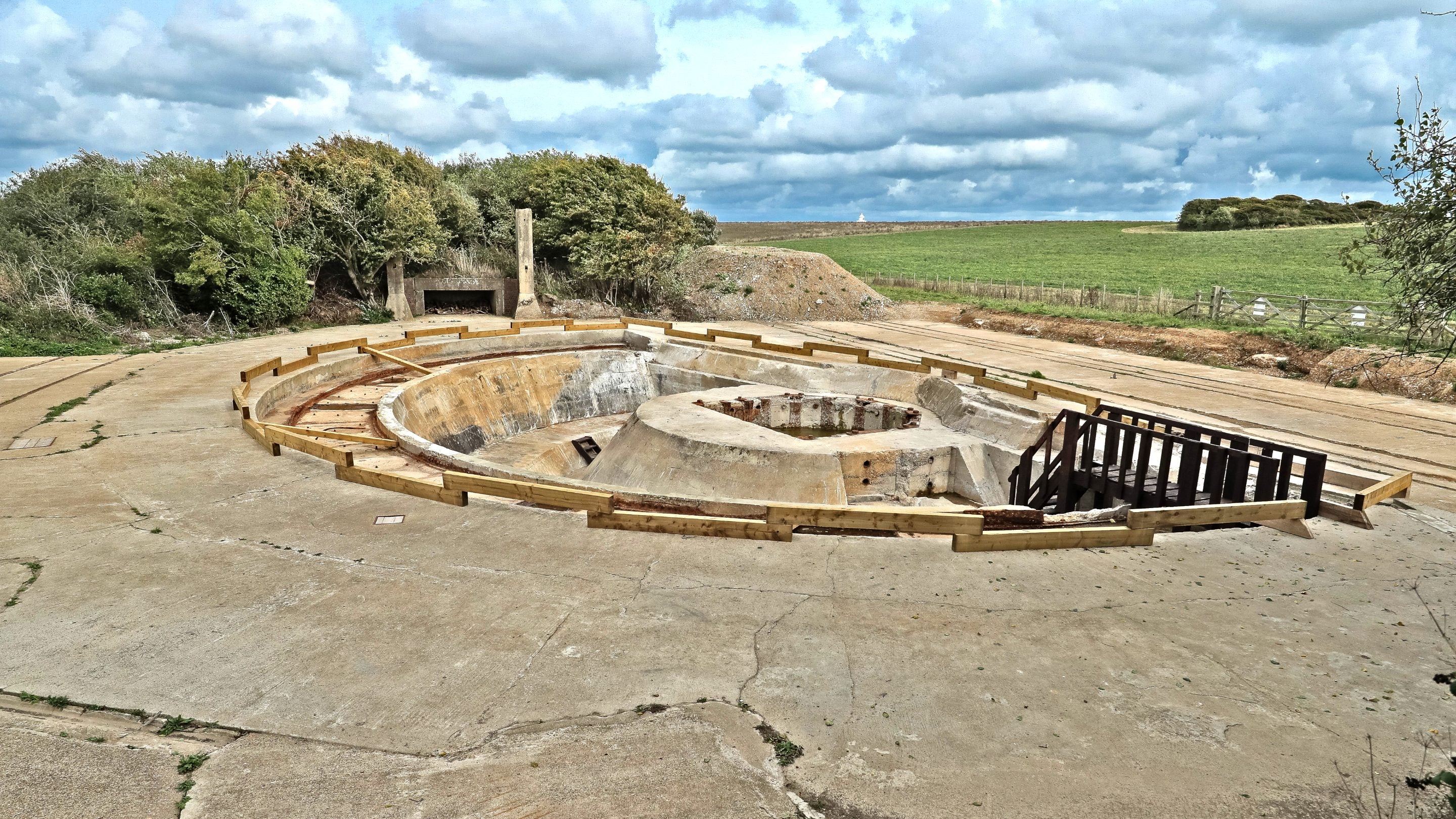 View of a semi-circular large concrete gun emplacement with scattered clouds