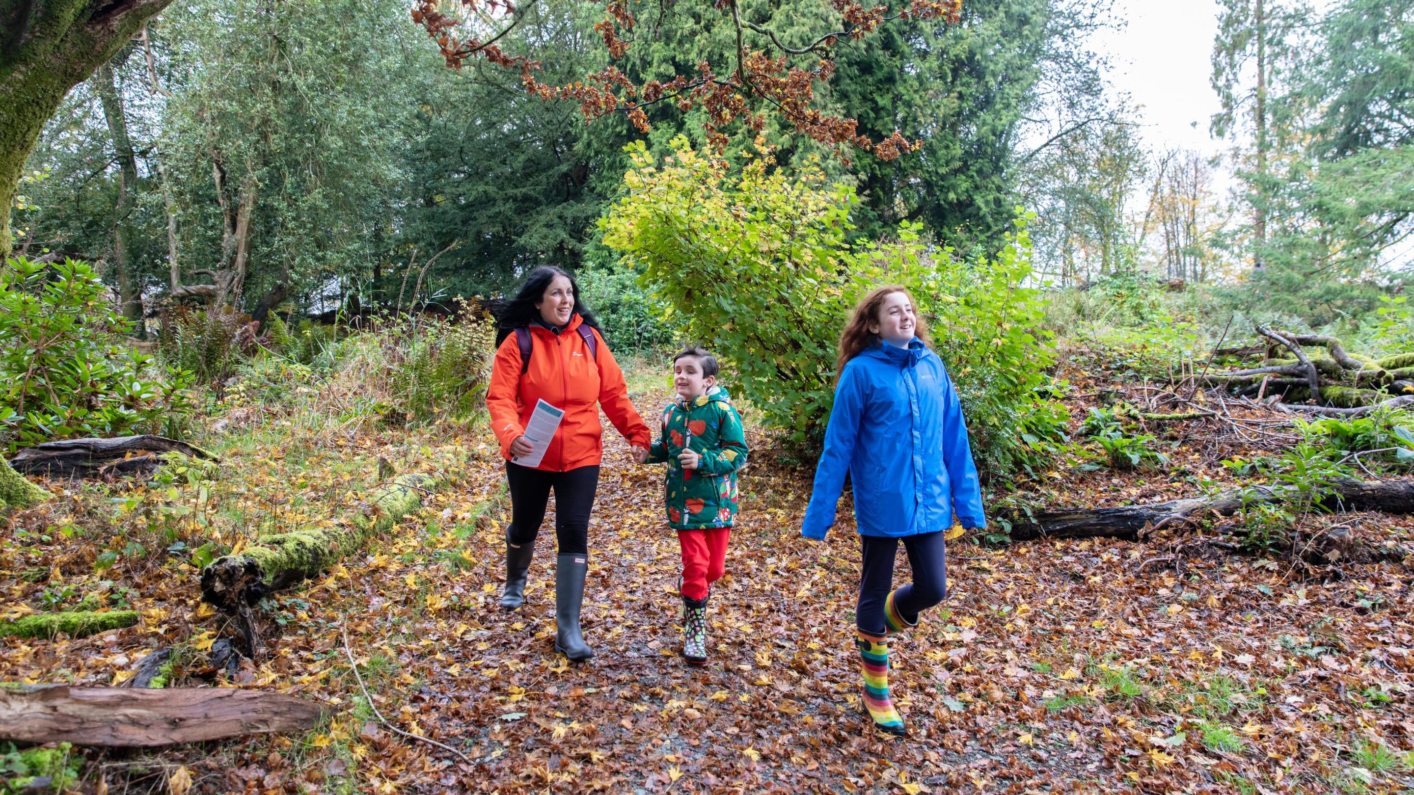 A family walking through the grounds of Wray Castle, Cumbria, in autumn