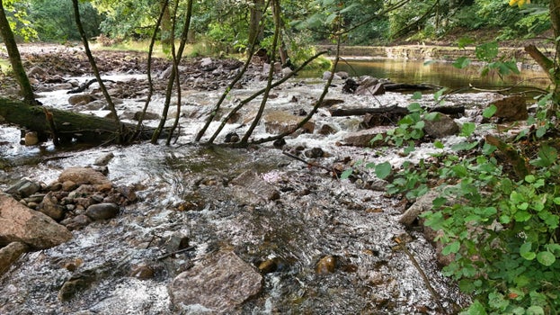A river with water flowing down a boulder cascade, which has replaced the weir