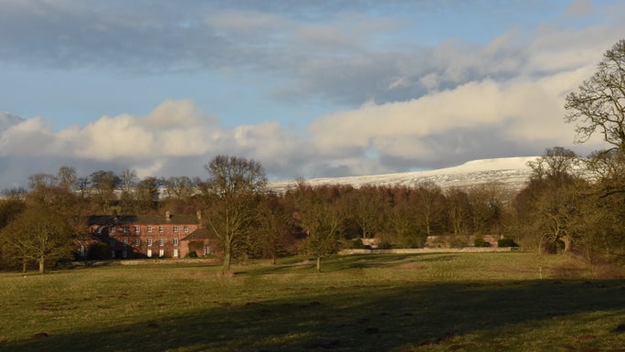A view of Acorn Bank's mansion and woodland from the surrounding estate