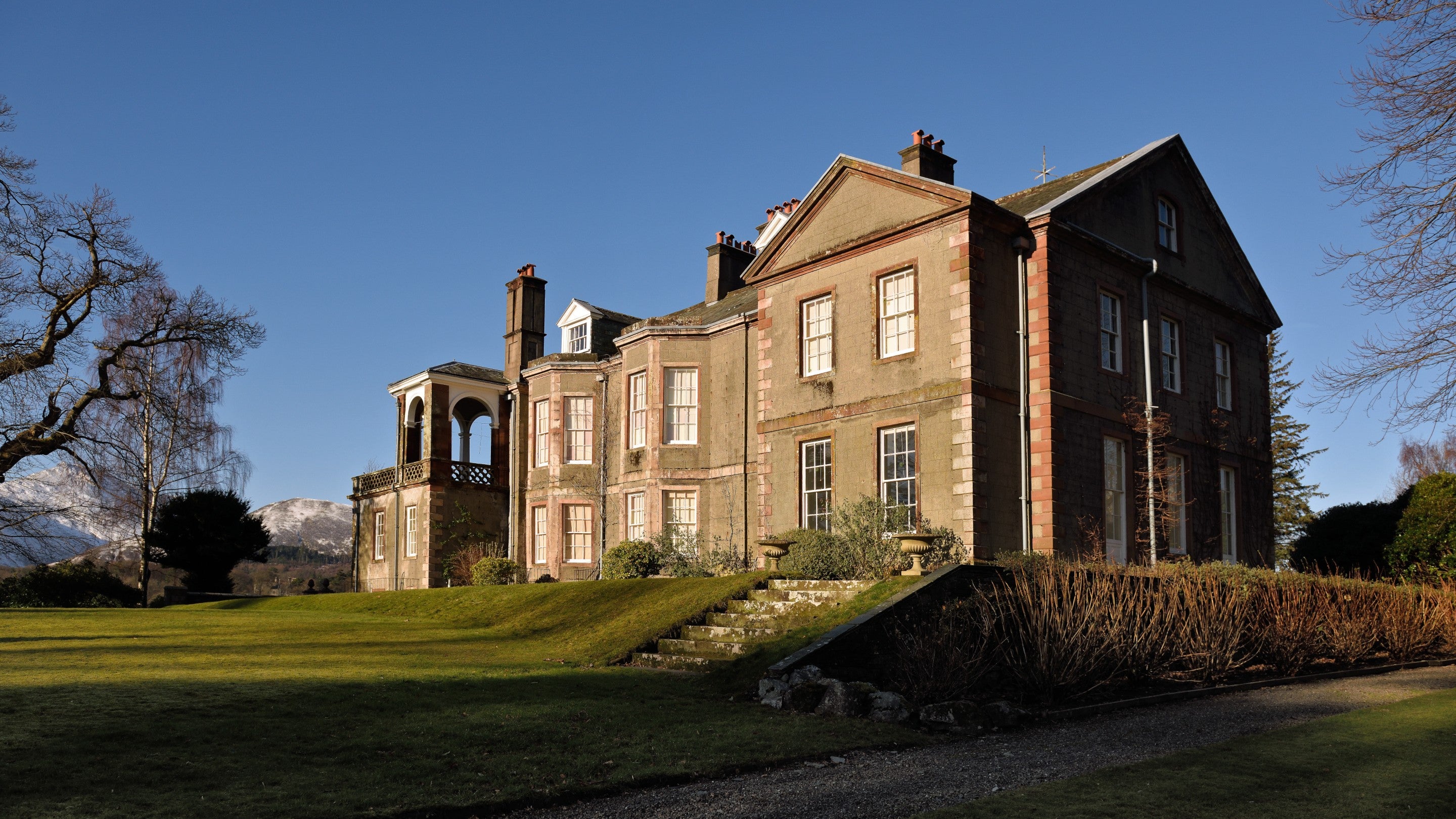 View of Derwent House from Derwent Island on Derwent Water under a clear blue sky, Lake District
