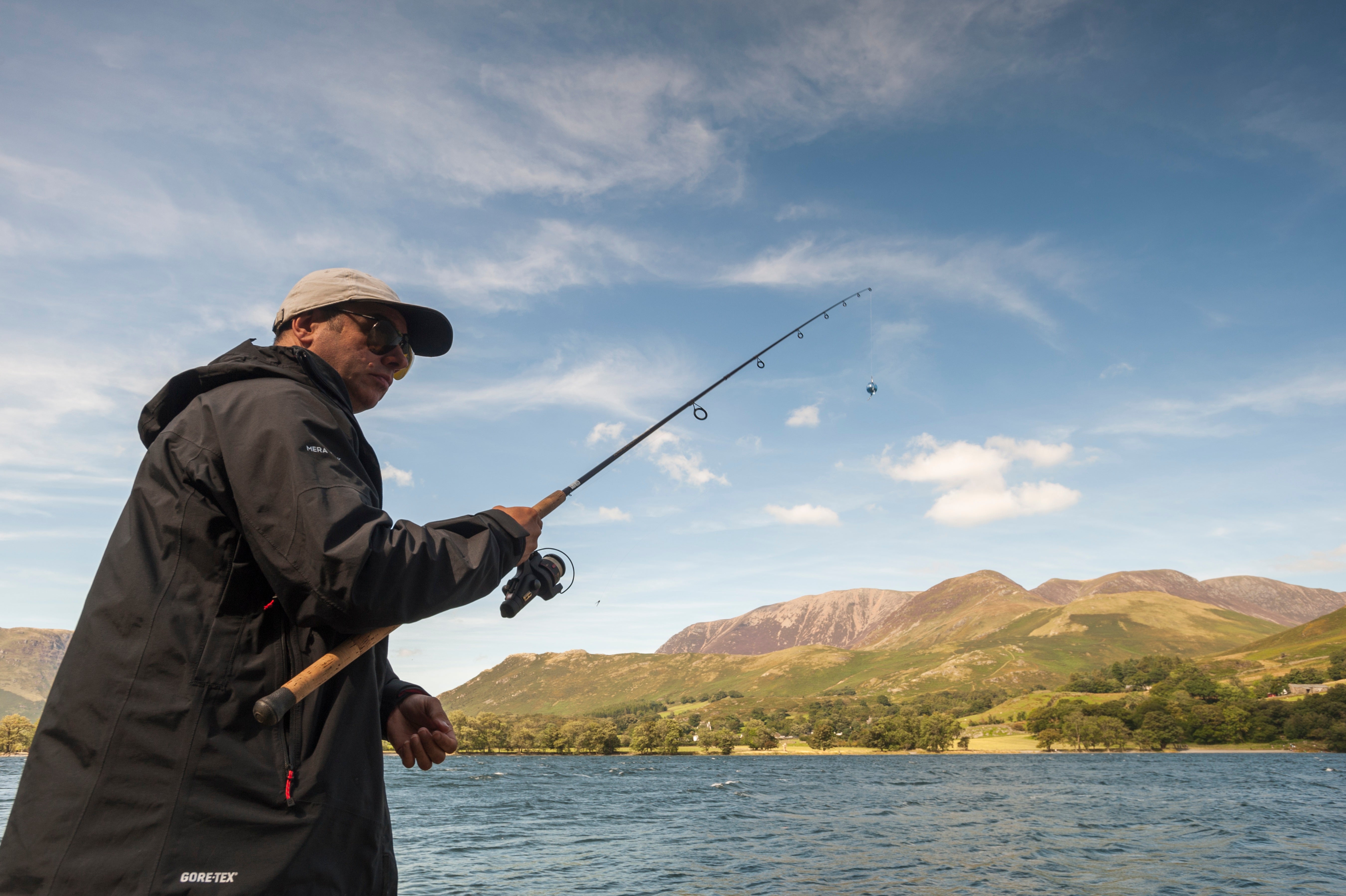 Man with baseball cap and sunglasses holding a rod fishing on Buttermere