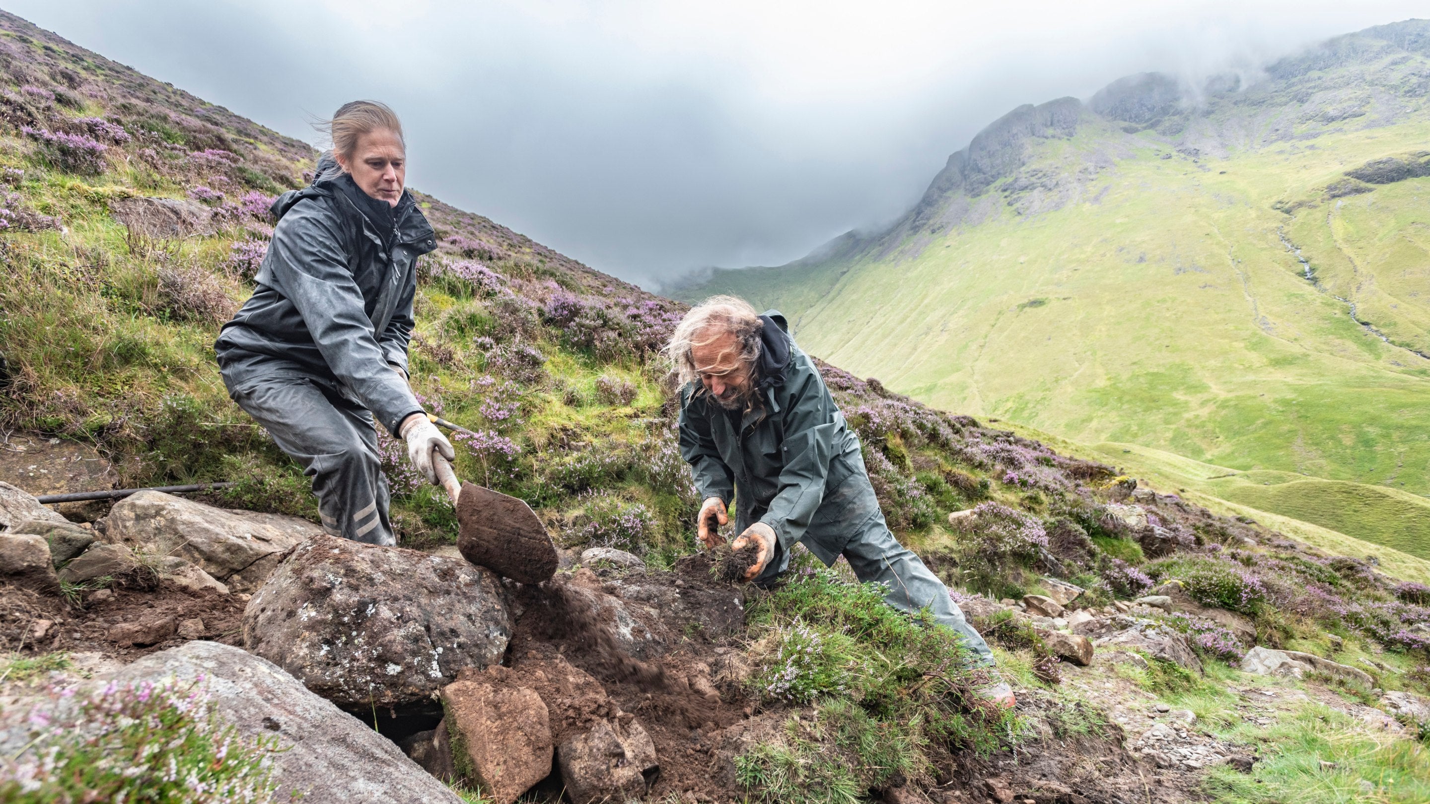 Two rangers work to repair a mountainside footpath