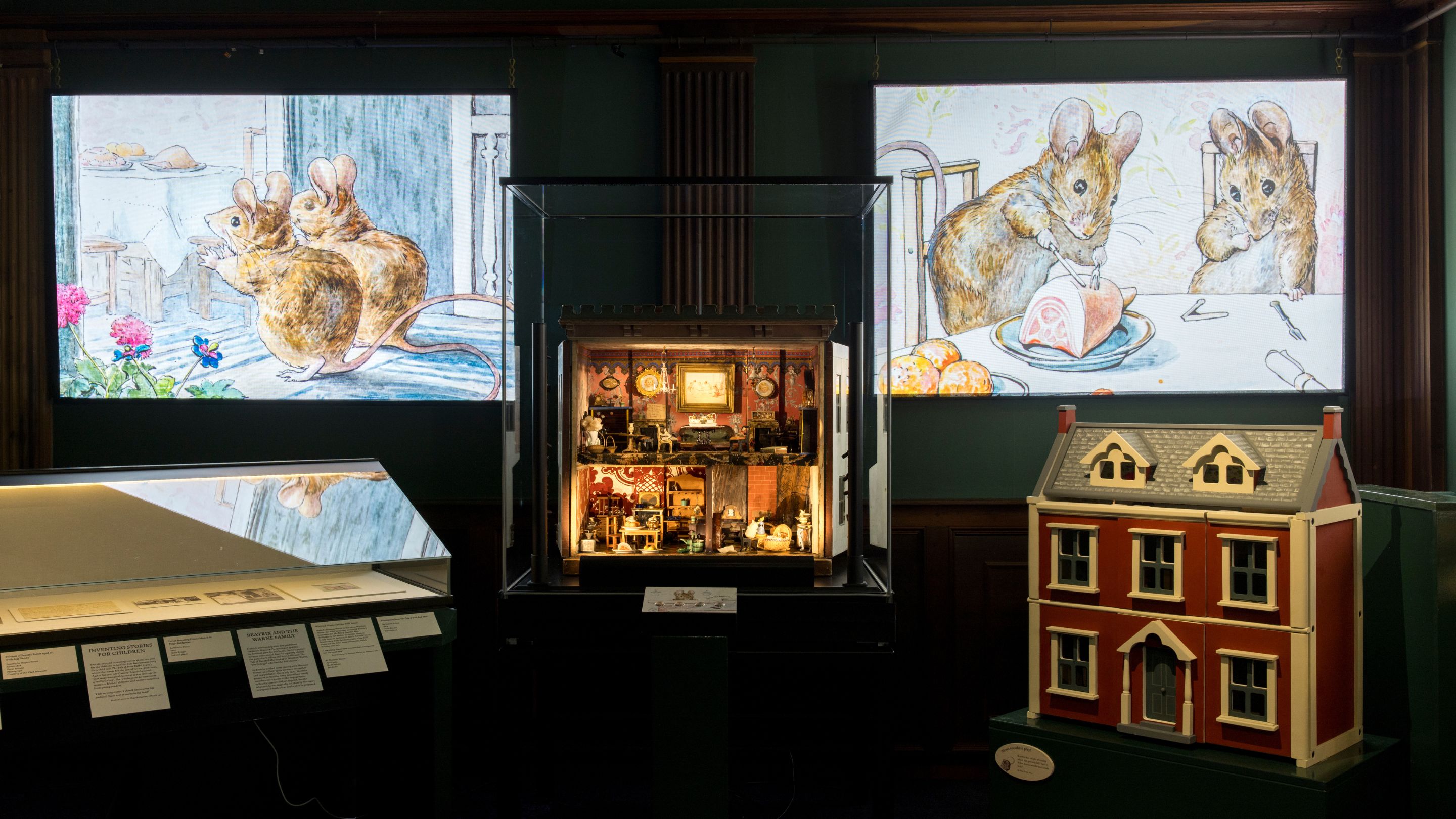 Interior of a room with display cabinets, a dolls' house and projections of mice from 'the Tale of Two Bad Mice' on the walls.