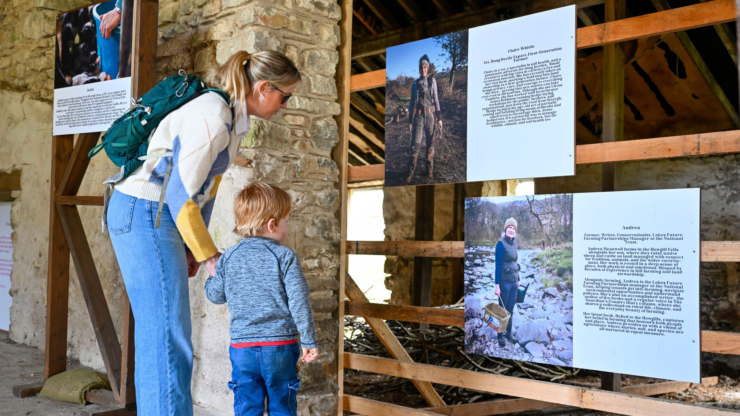 Adult and child reading exhibition panels inside a stone barn at Sizergh.