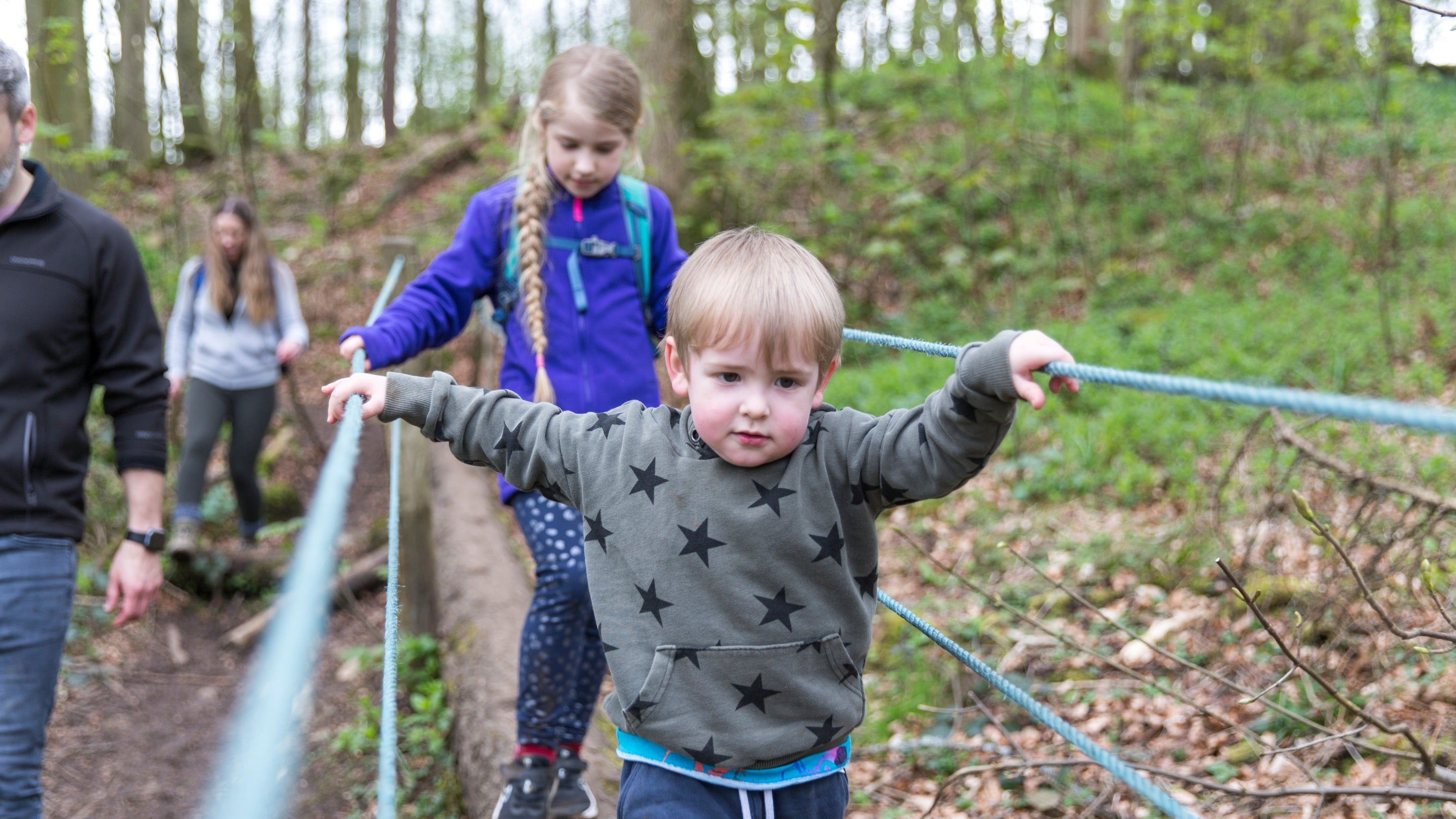 Family on the wild trail in the woodland at Sizergh Castle, Cumbria