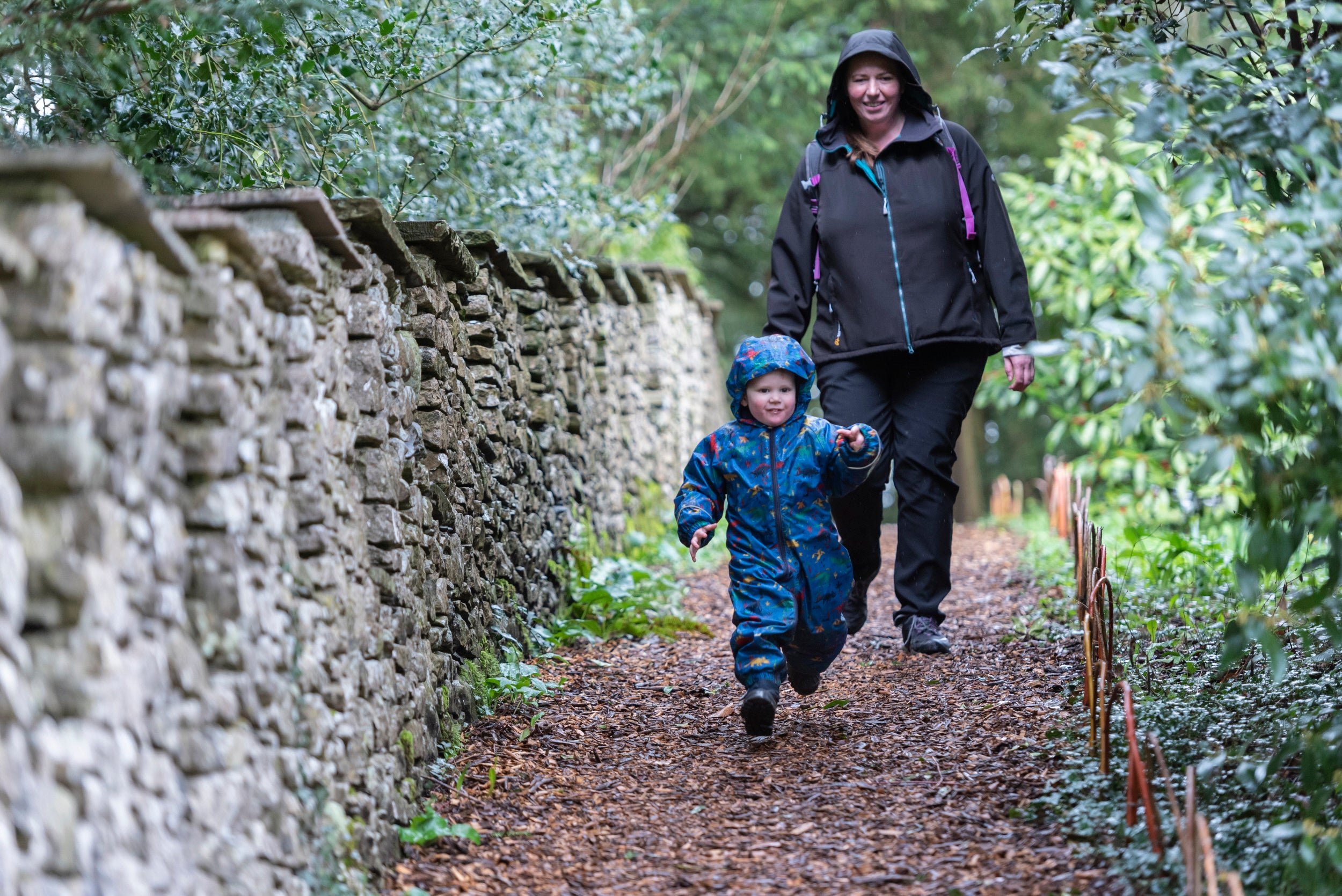 A mother and young child walking down a path at Sizergh during the winter. The child is wearing a blue snowsuit, and the mother is wearing a waterproof coat.