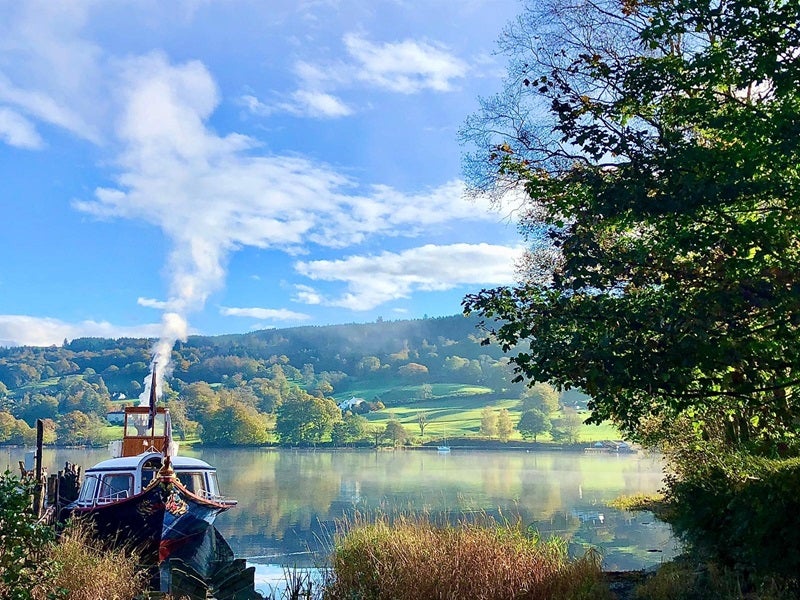 An autumnal scene showing the jetty and Gondola steaming ready for the day ahead with autumnal colours in the hills in the background