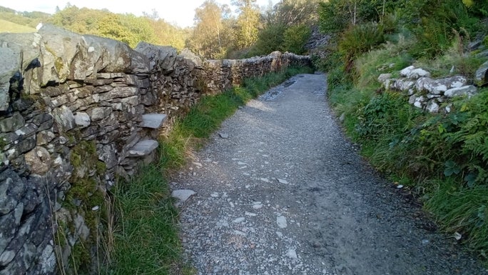 Gravel footpath between two drystone walls along the edge of woodland, Little Langdale, Cumbria