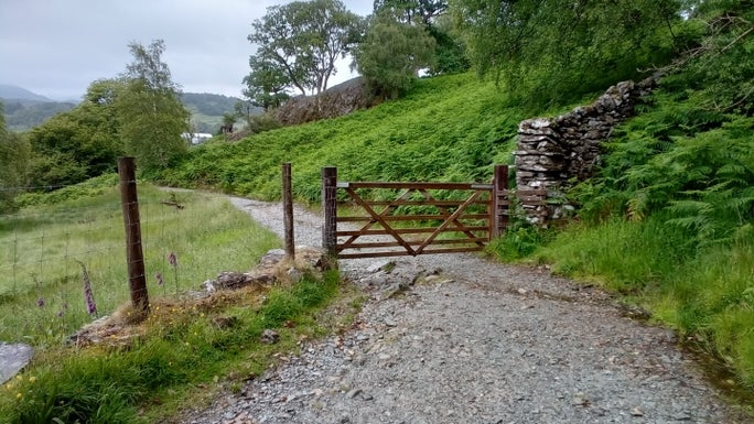 Gravel footpath with metal fencing on the left and a grassy banking on the right, Hodge Close, Cumbria