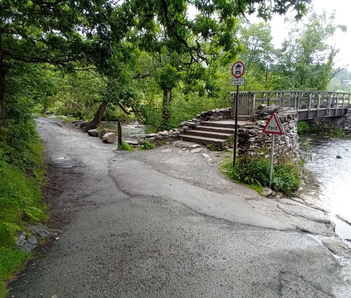 Stone footpath next to the river and old stone bridge, Tilberthwaite, Cumbria
