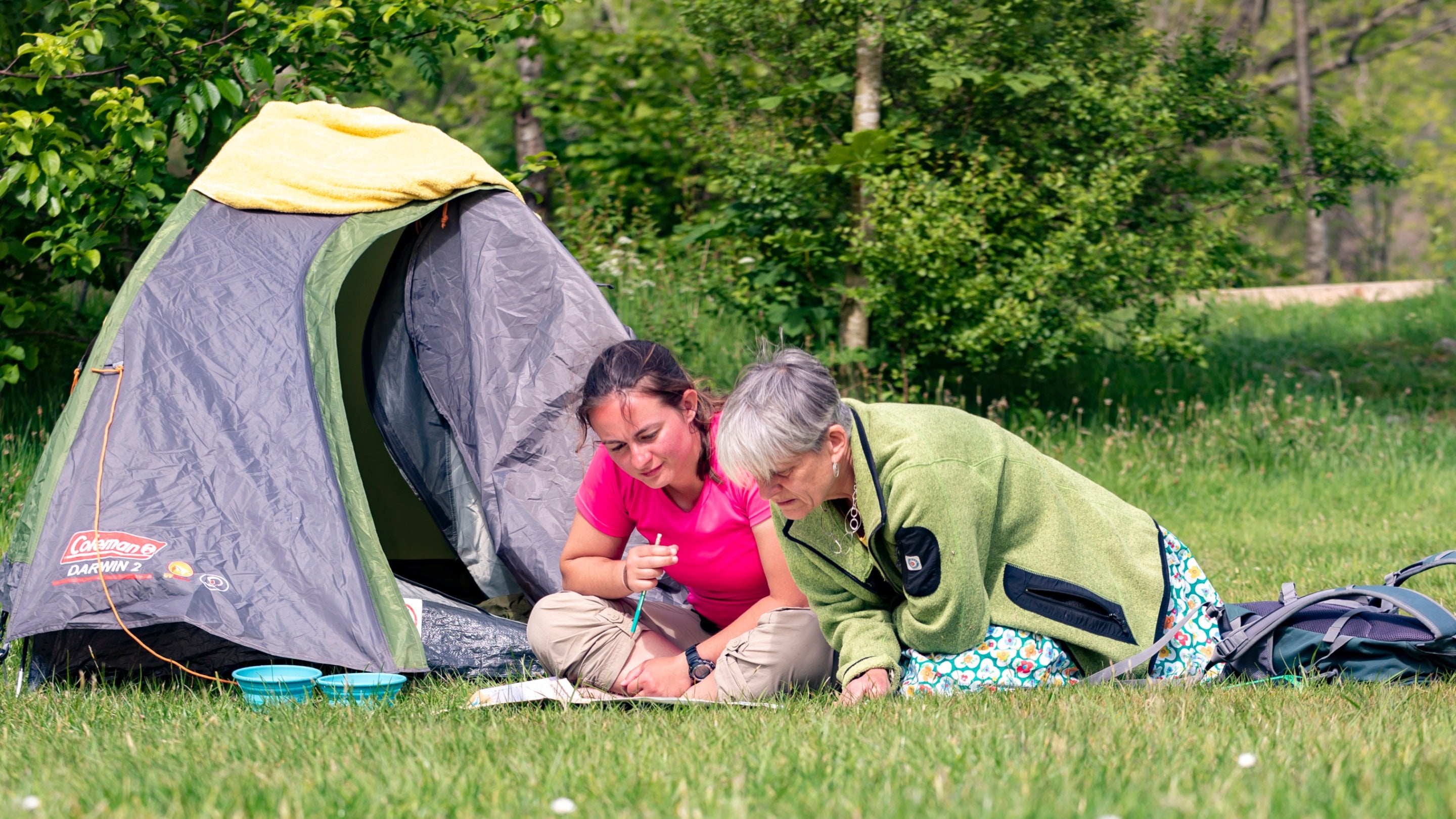 Two visitors sit on the grass in front of a tent at Wasdale Campsite, Cumbria
