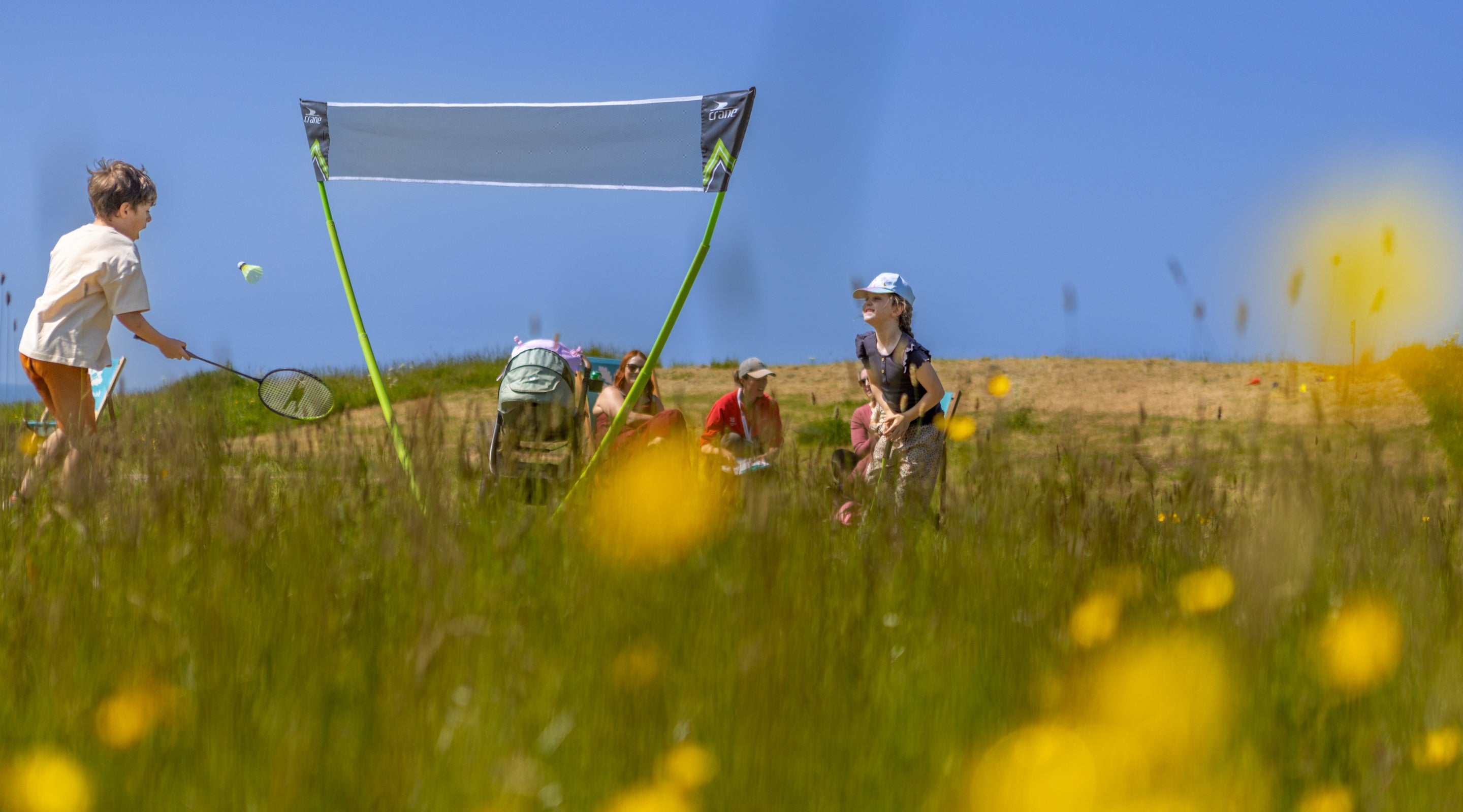 Children playing badminton among the wildflower fields on the Whitehaven Coast