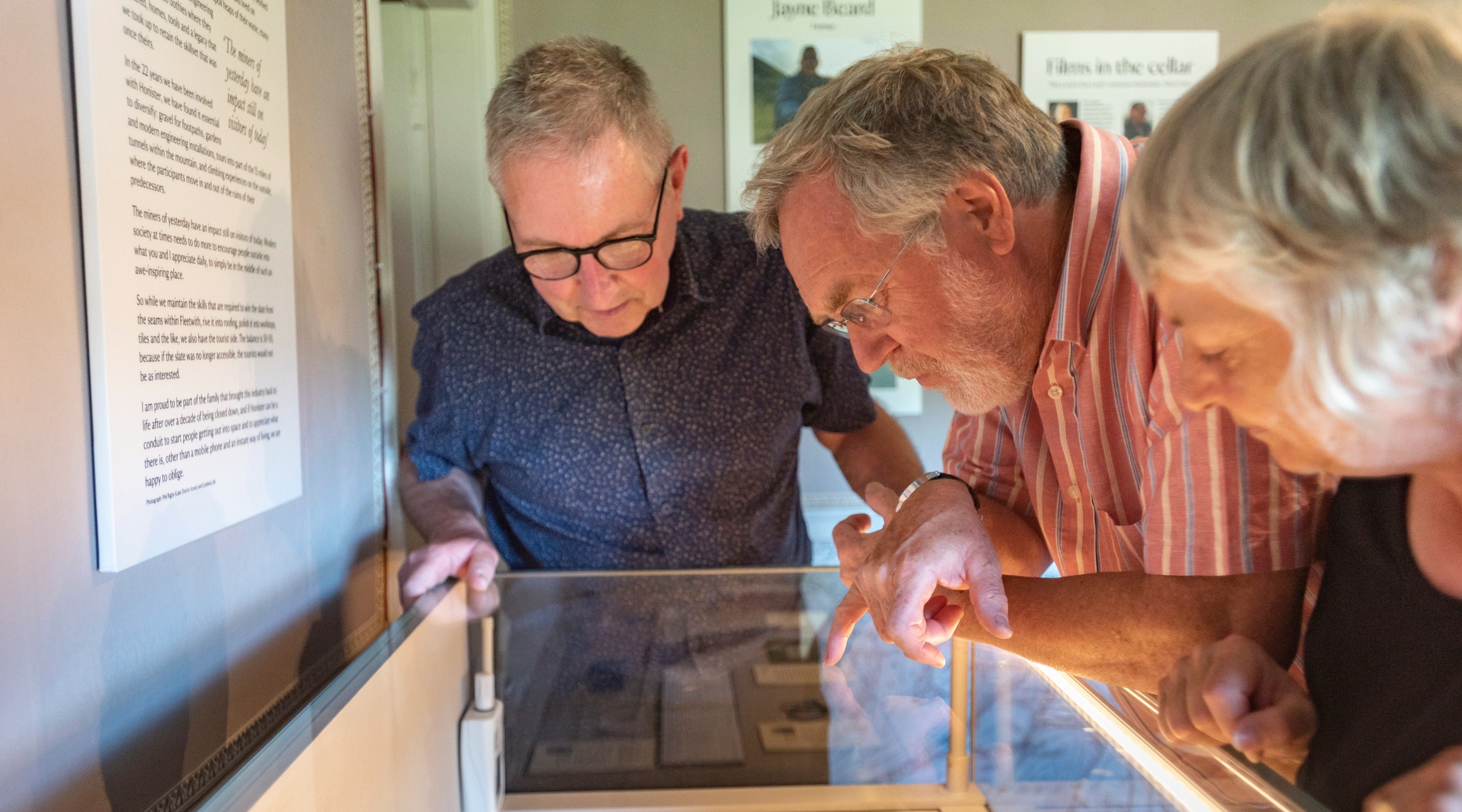 Three people gaze into a display case in the exhibition room at Wordsworth House and Garden