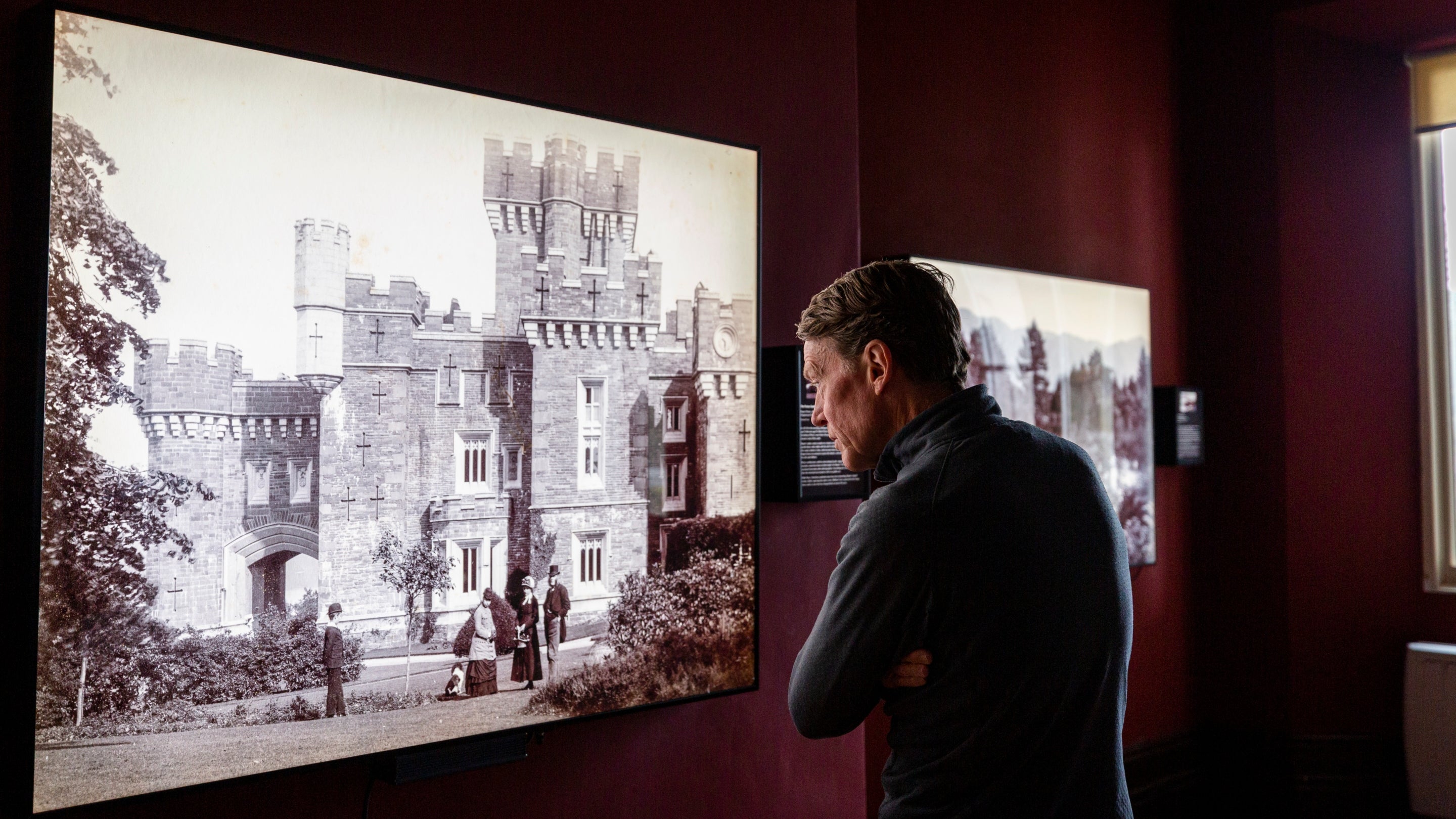 A visitor looks at a lightbox display showing an old photograph of the castle