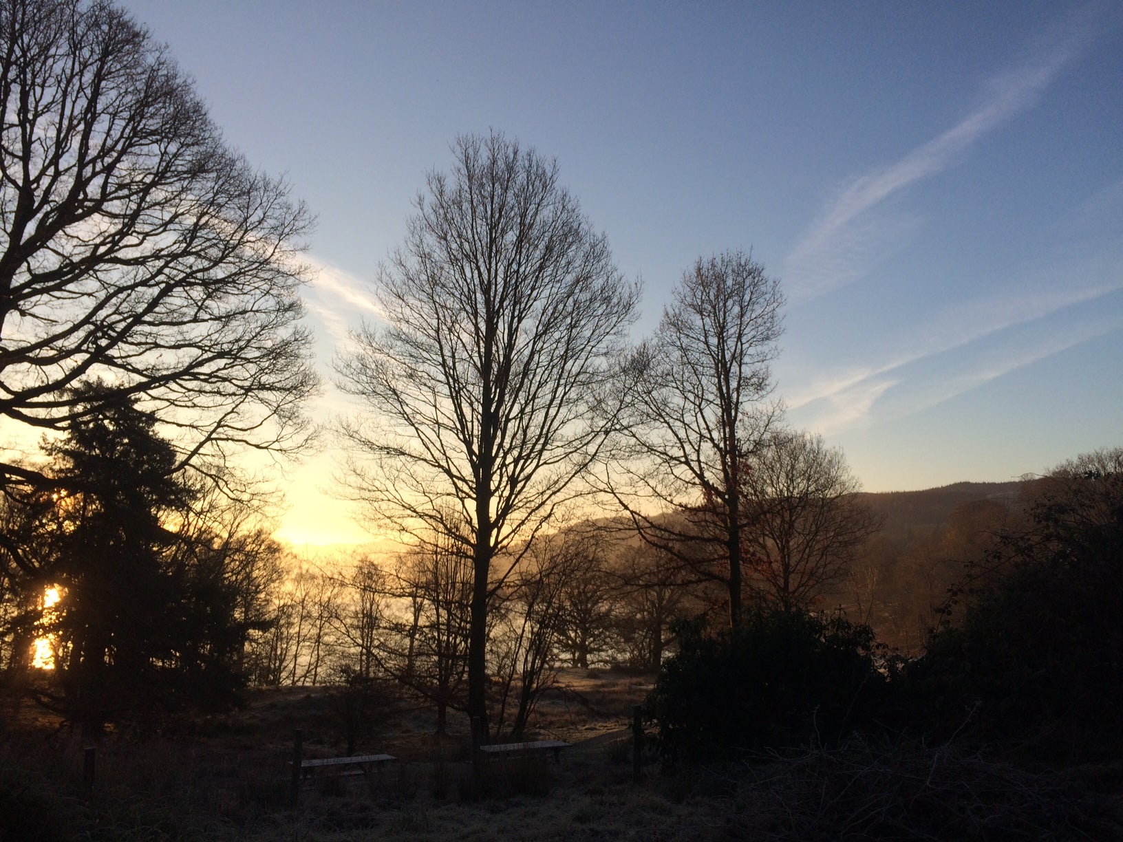 A cold winter view of the shore of Windermere through the bare trees and winter coloured sky at Wray, Cumbria