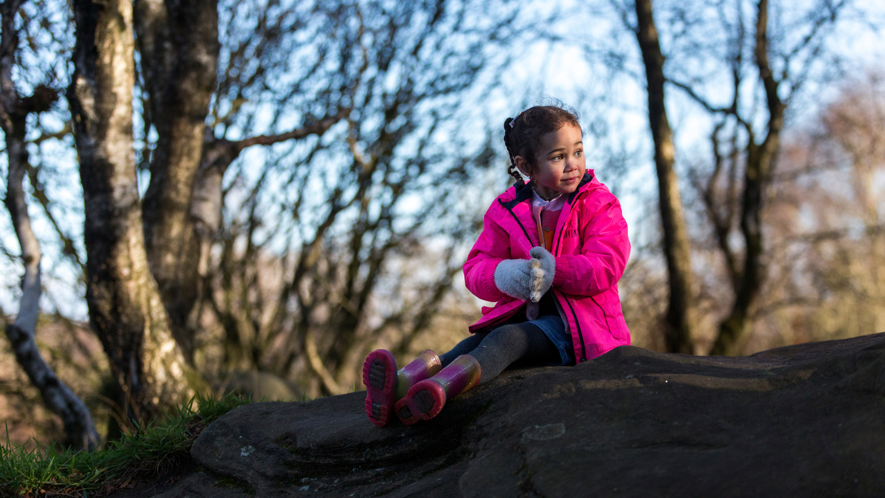 Girl in pink coat and wellies playing outside in winter