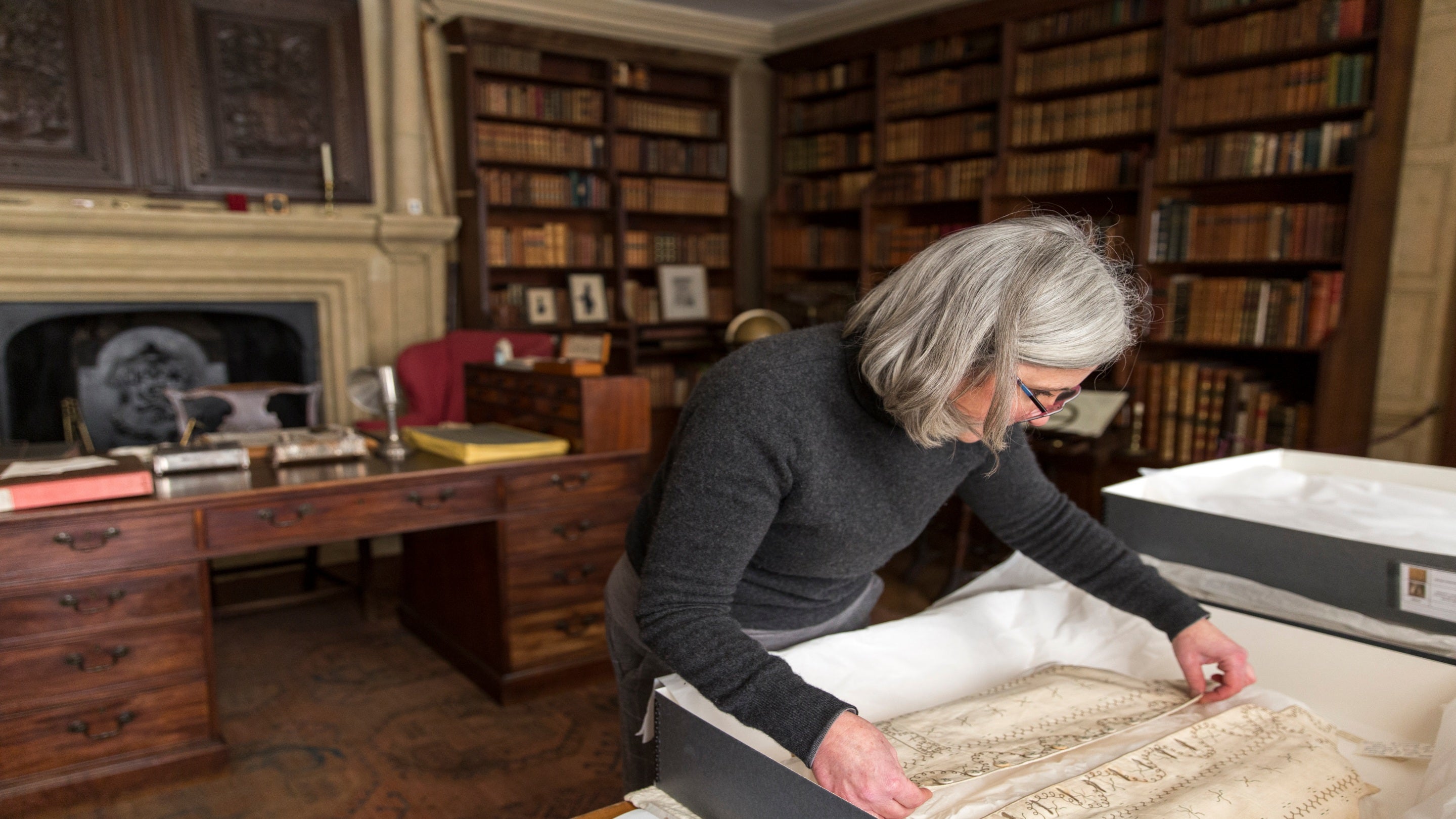 Textile conservator working on 18th-century waistcoats in the Book Room at Canons Ashby, Northamptonshire