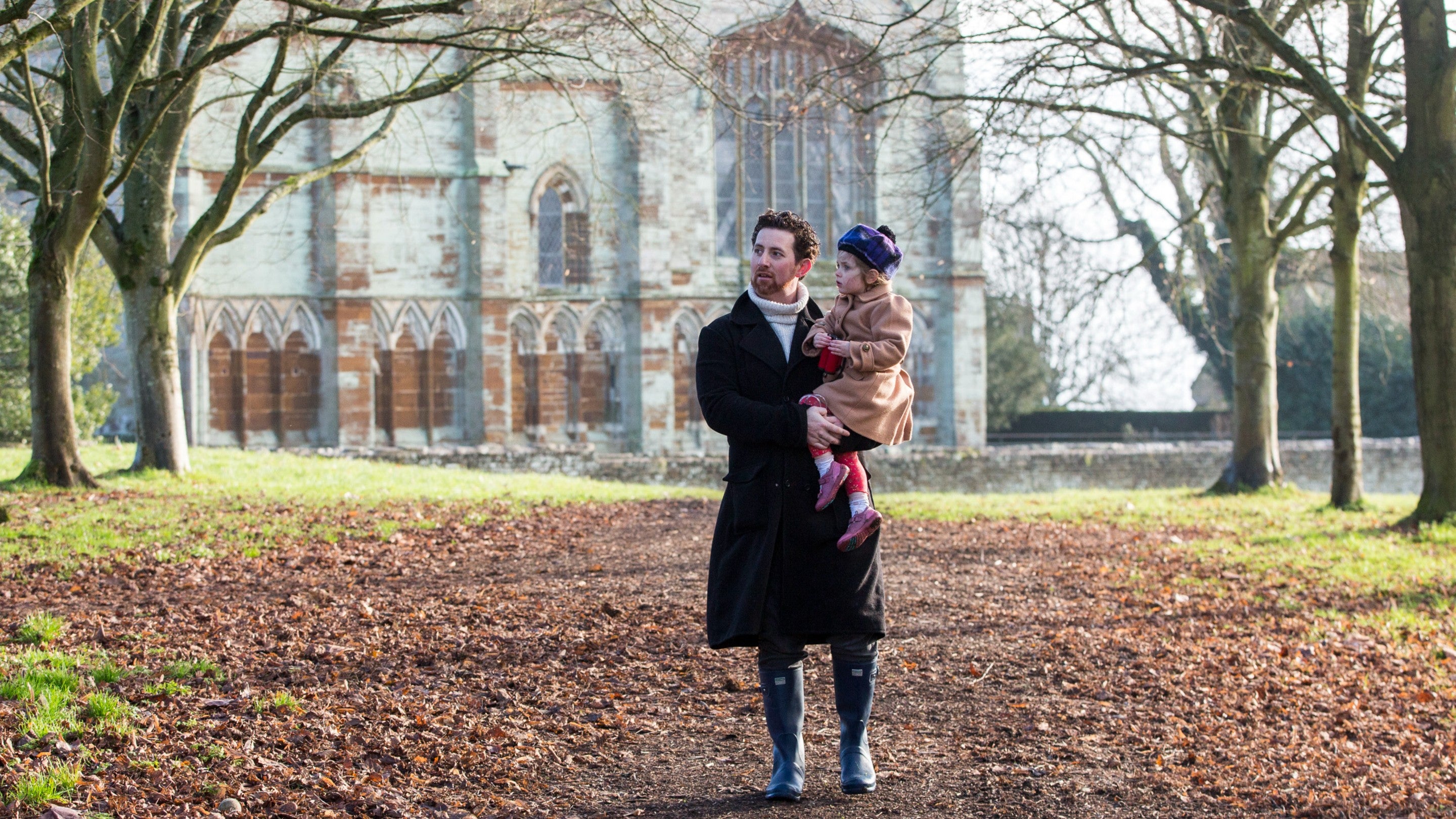 Father holding his young daughter in his arms as they walk through
