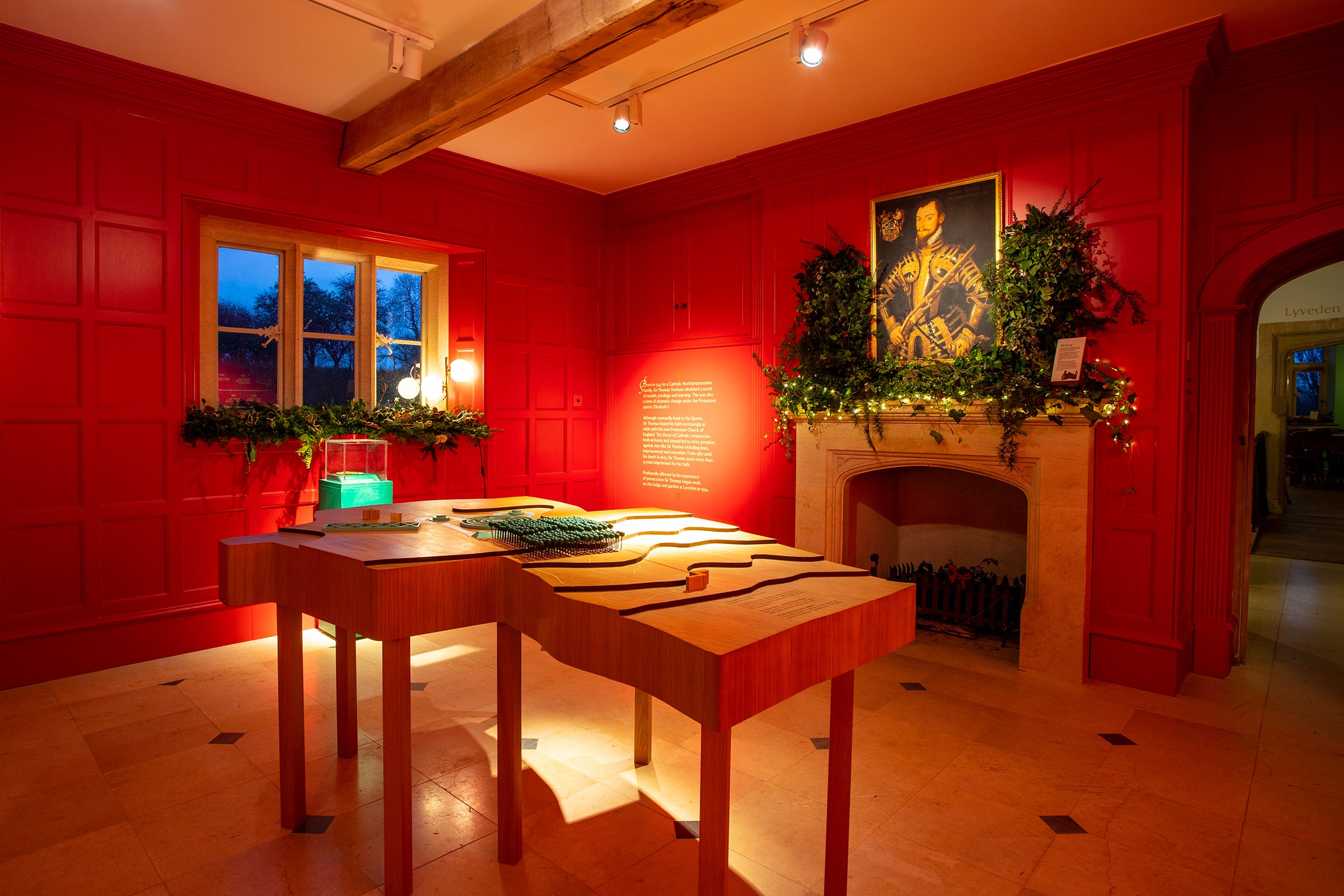 The red room at Lyveden decorated for Christmas with window sills and mantlepiece decked with traditional greenery.