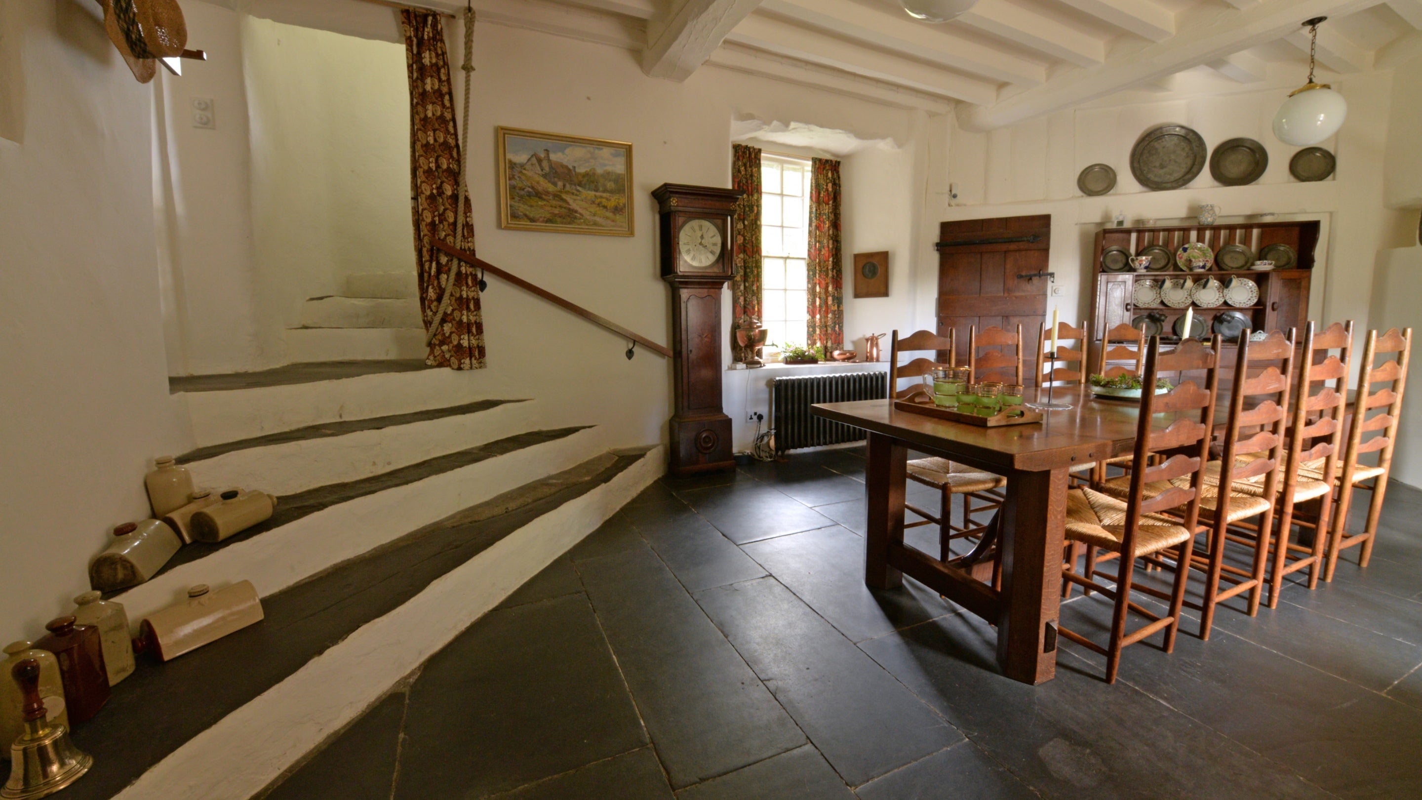 A view of the Dining Room at Stoneywell with a slate floor, steps leading up to the left and the dining table and chairs on the right